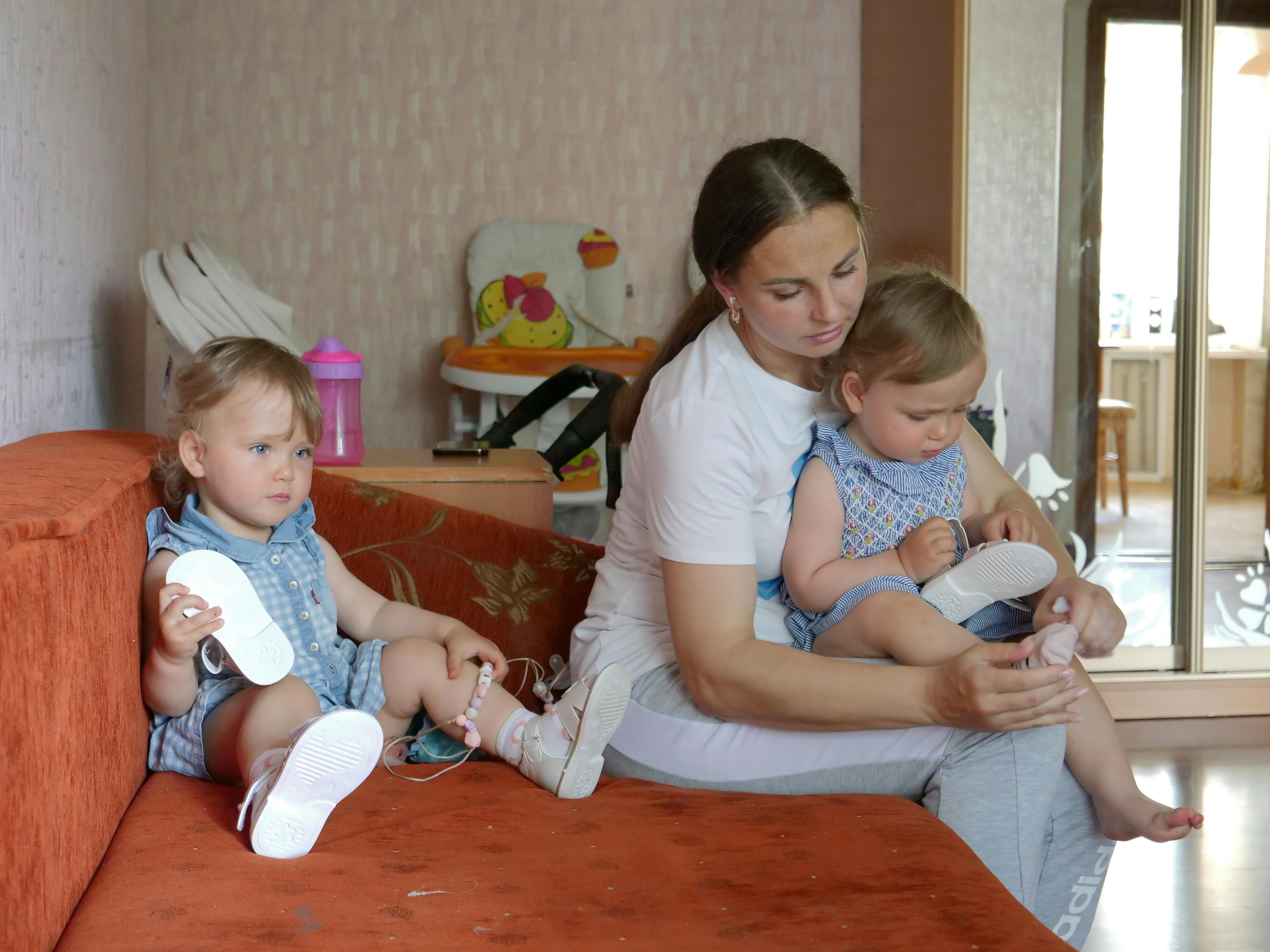 Yulia Supereka, 33 anni, mette scarpe e calzini ai suoi gemelli di due anni Mariia e Sophia prima di una passeggiata. La famiglia di Yulia, fuggita dagli orrori della guerra a Kiev, ha ricevuto una mano grazie al programma di assistenza in denaro dell'UNICEF.