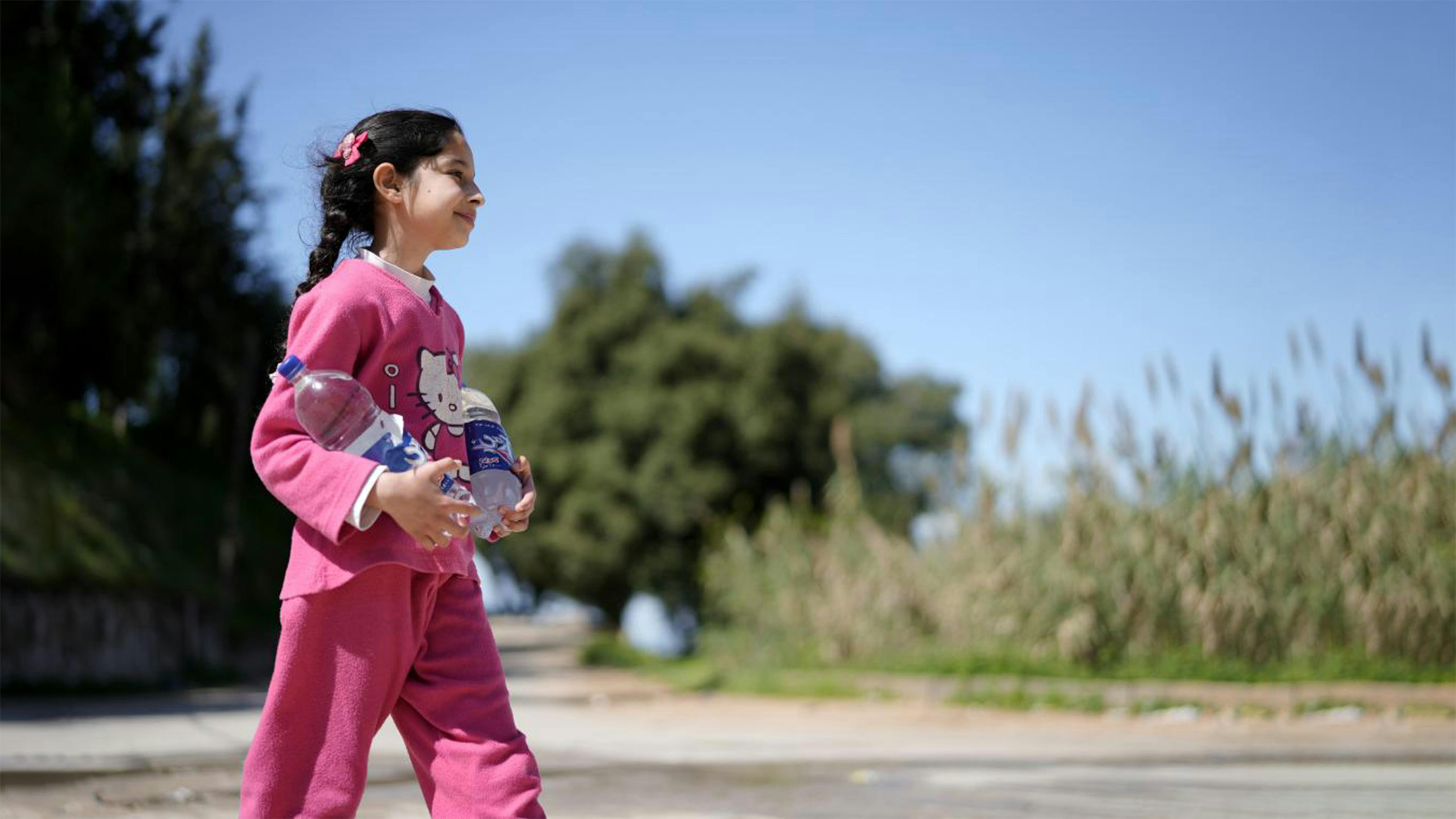 "Vengo con mio padre ogni giorno per aiutarlo a prendere l'acqua per la mia famiglia", dice Syrine, 10 anni, mentre ha due grandi bottiglie di plastica appena riempite 