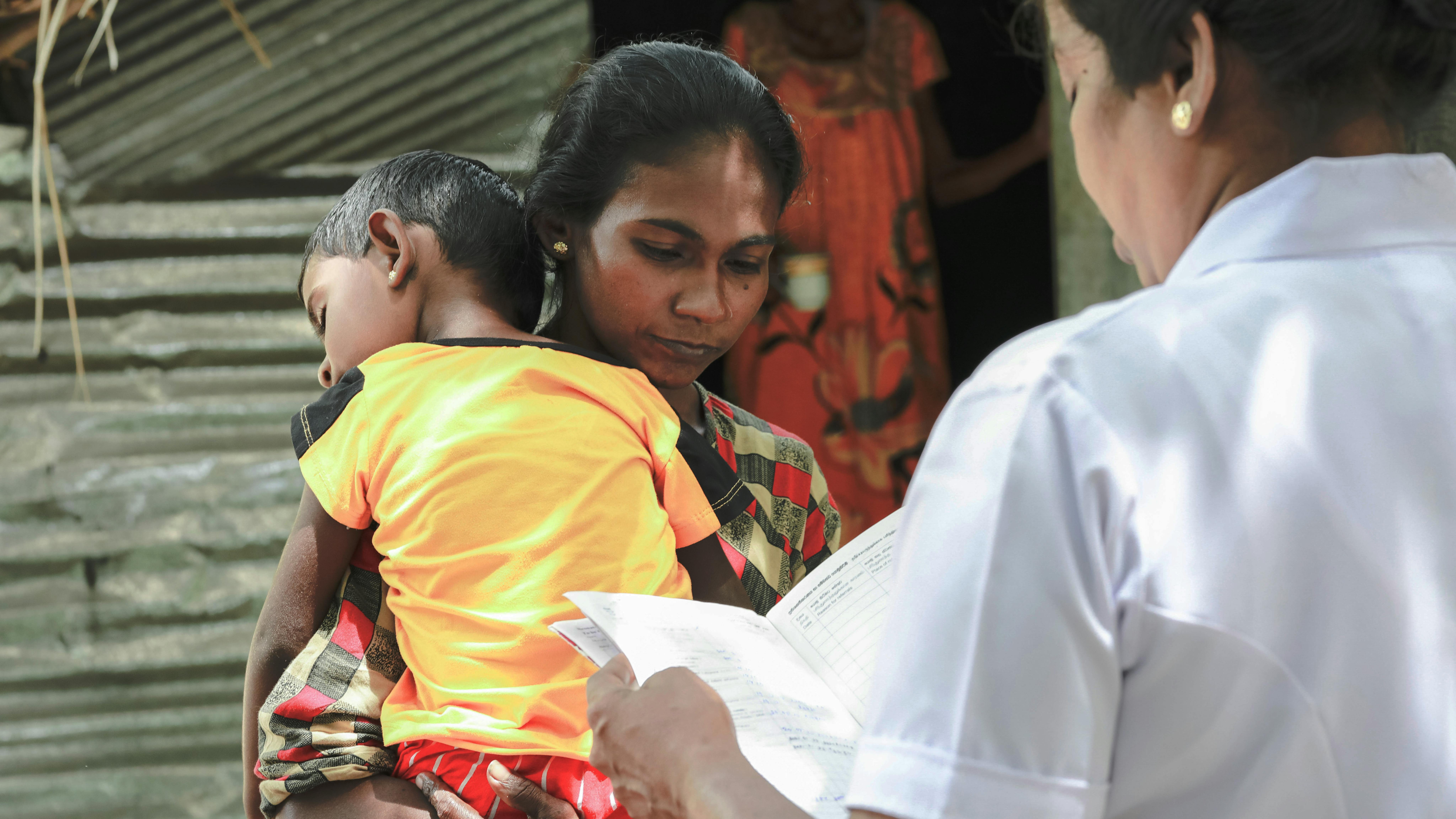 Sri Lanka, una mamma con in braccio il suo bambino malnutrito parla con un ostetrica
