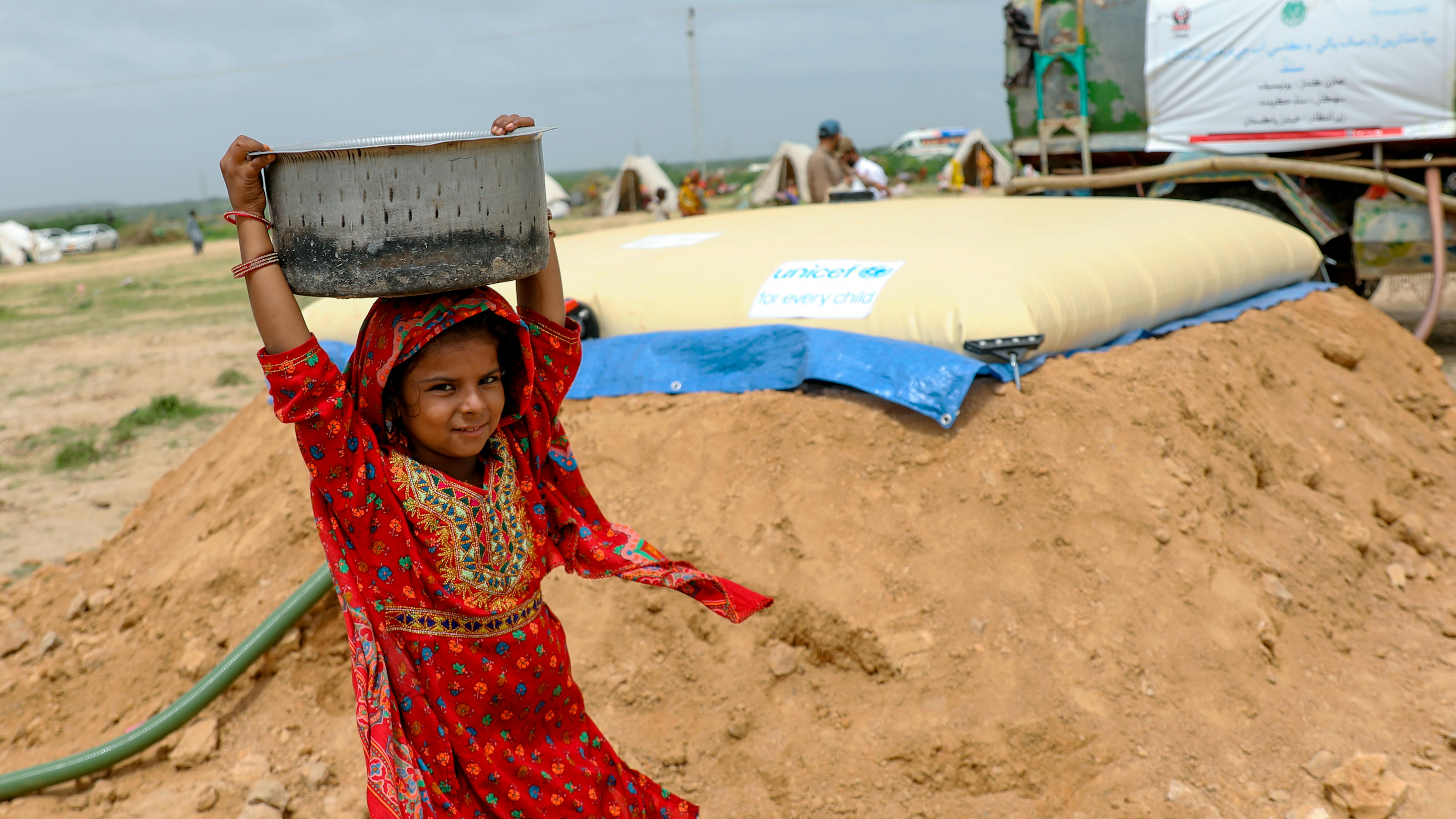 Pakistan, Arshia, 9 anni, torna alla sua tenda dopo aver raccolto l'acqua da una cisterna installata dall'UNICEF nel campo dove lei e la sua famiglia si sono rifugiate