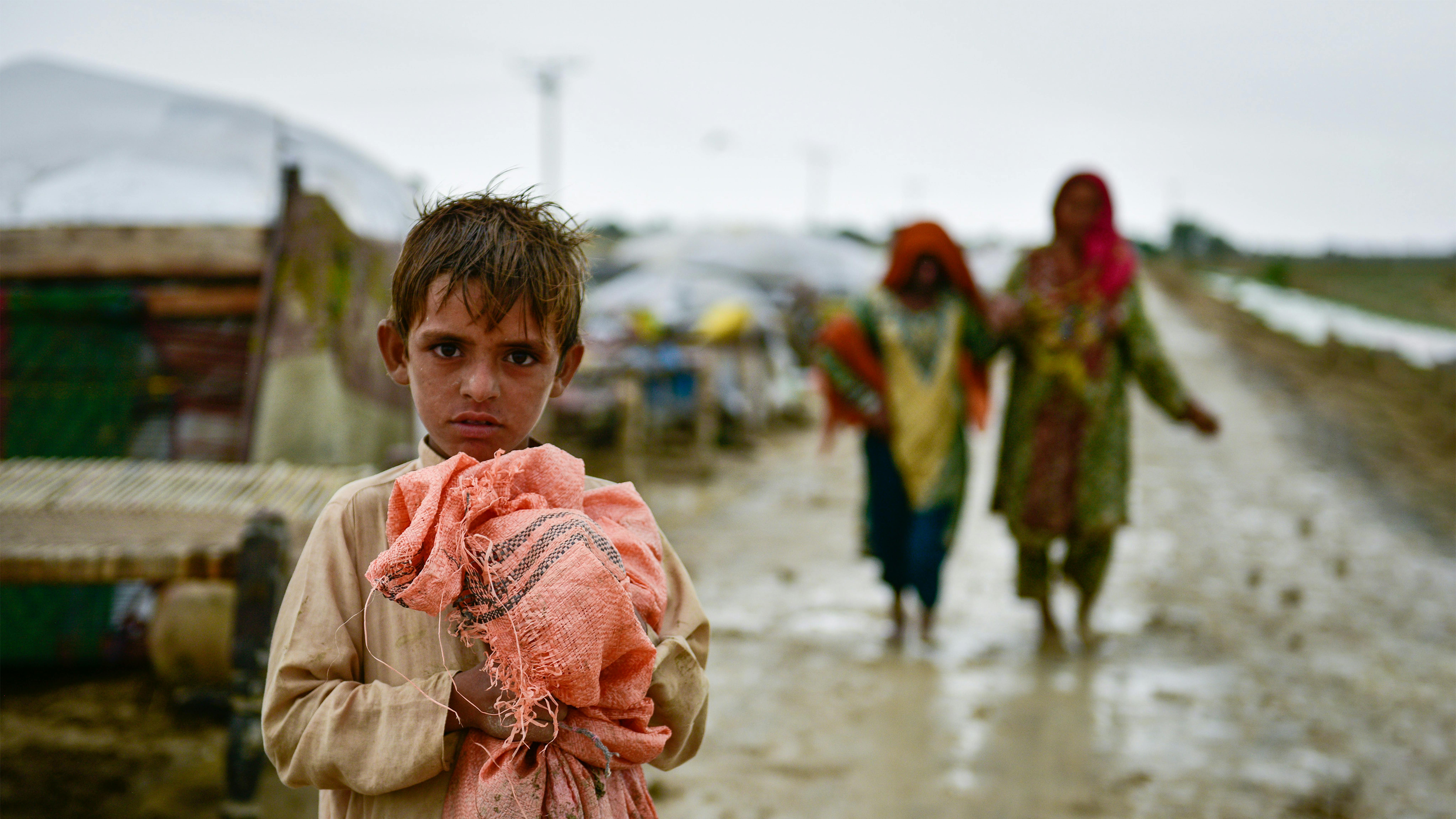 Pakistan - Un bambino con le sue poche cose  si sposta assime alla sua famiglia in aree più sicure dopo l'alluvione.