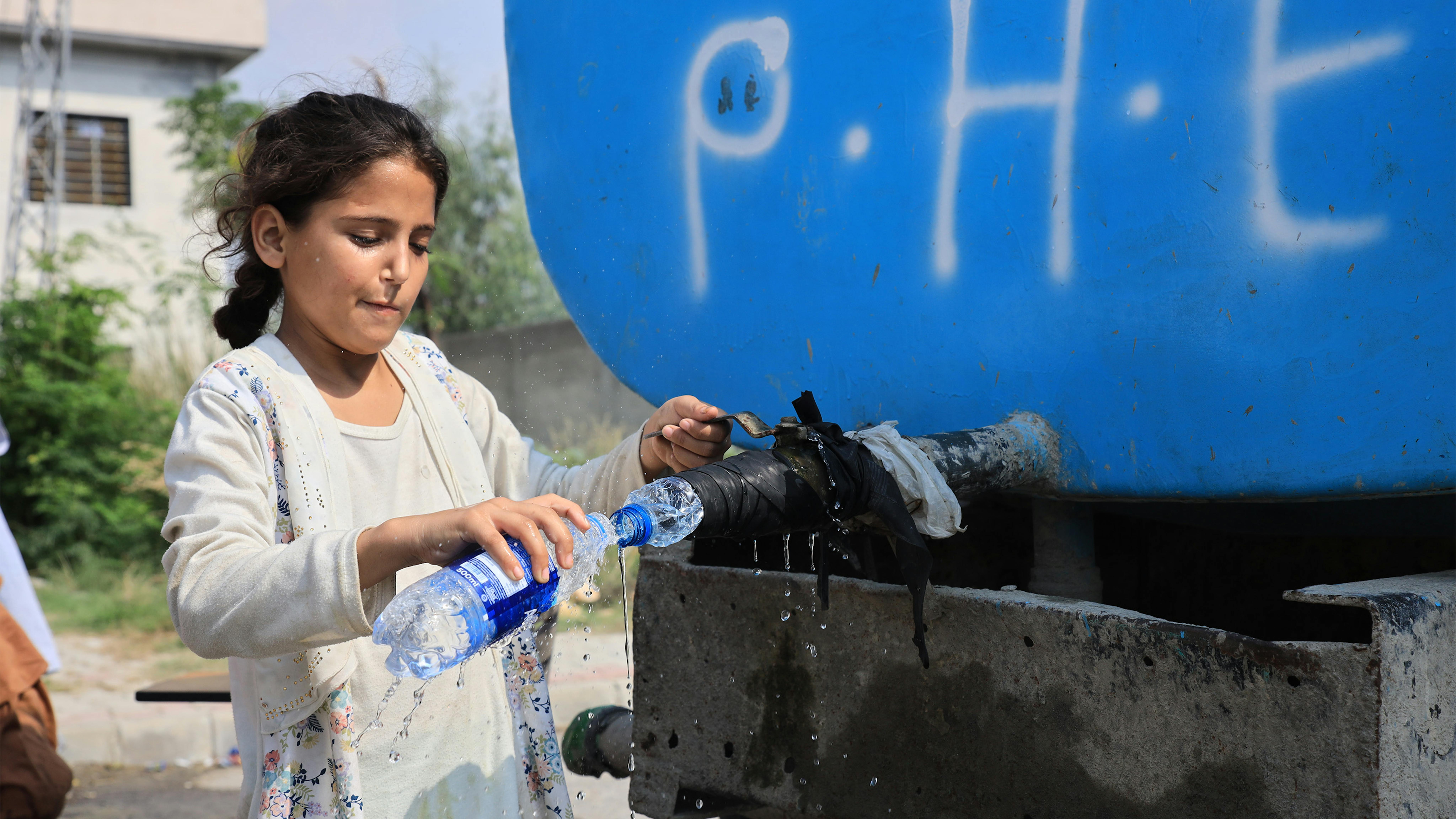 Pakistan, una bambina riempie una bottiglia d'acqua da una cisterna fornita dall'UNICEF