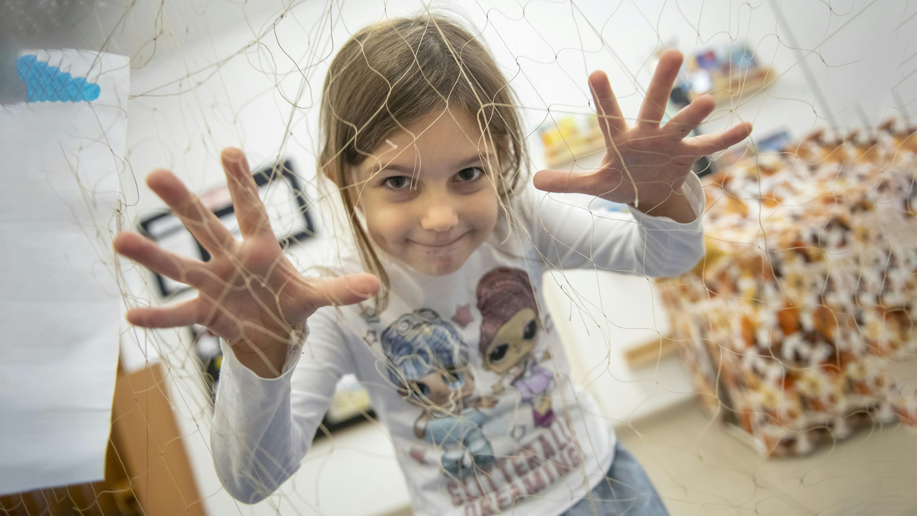 Una bambina che gioca, dietro una rete