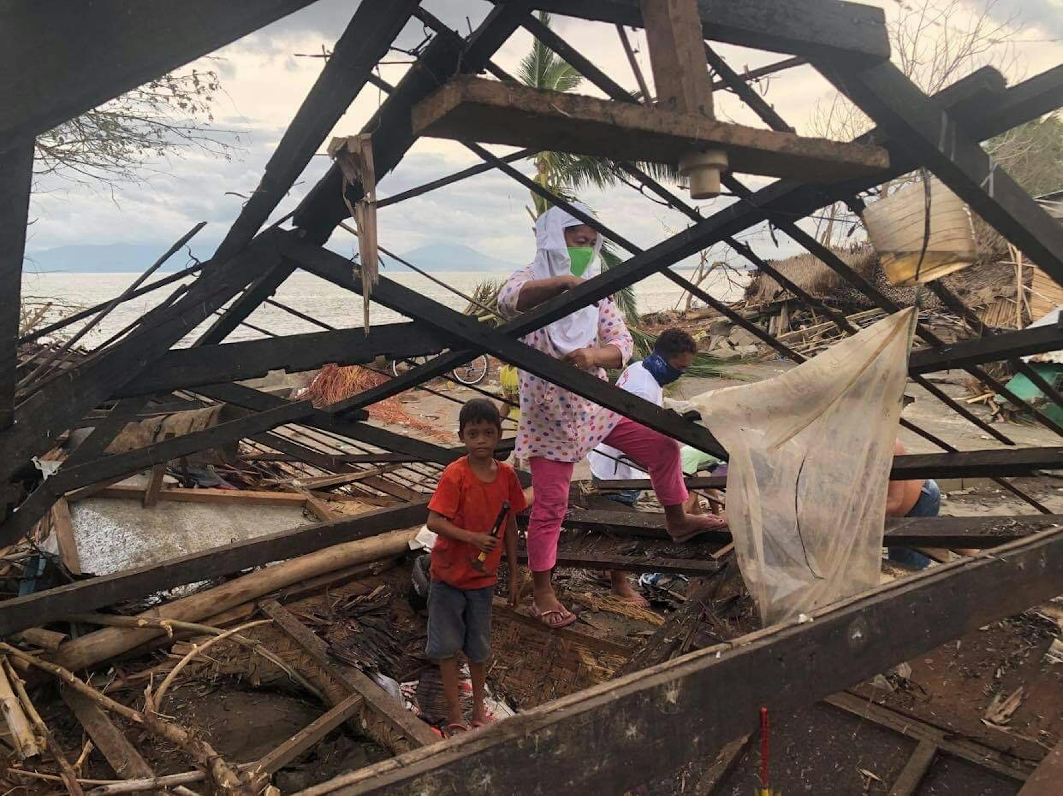 Un bambino con sua nonna ispezionano i resti della loro casa, spazzata via dal tifone Rolly, nel villaggio di Barangay, Sabang, San Jose nelle Filippine
