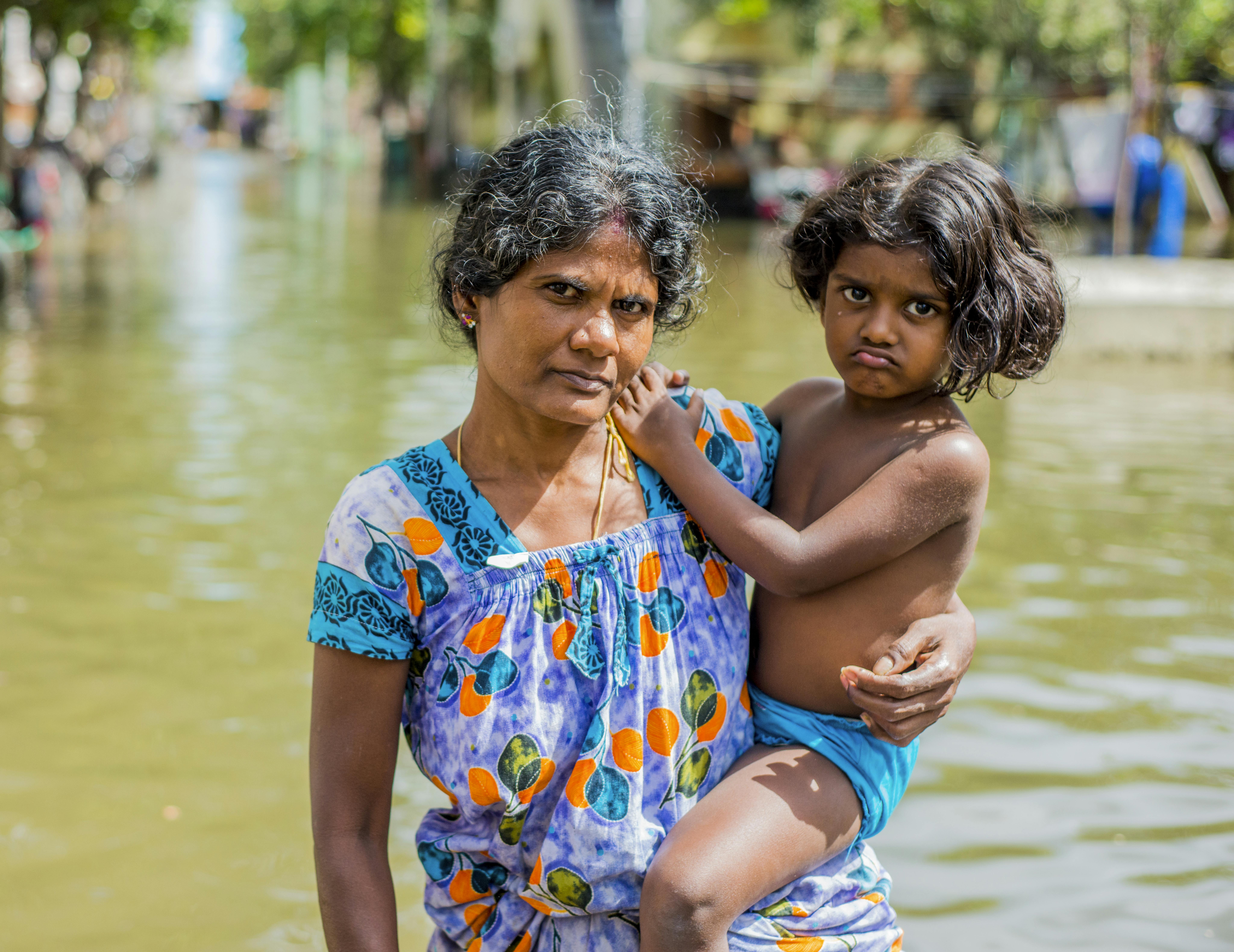 Una mamma con suo figlio attraversano le strade alluvionate dal ciclone Nirav, che ha colpito Tamil Nadu, in India nel 2021