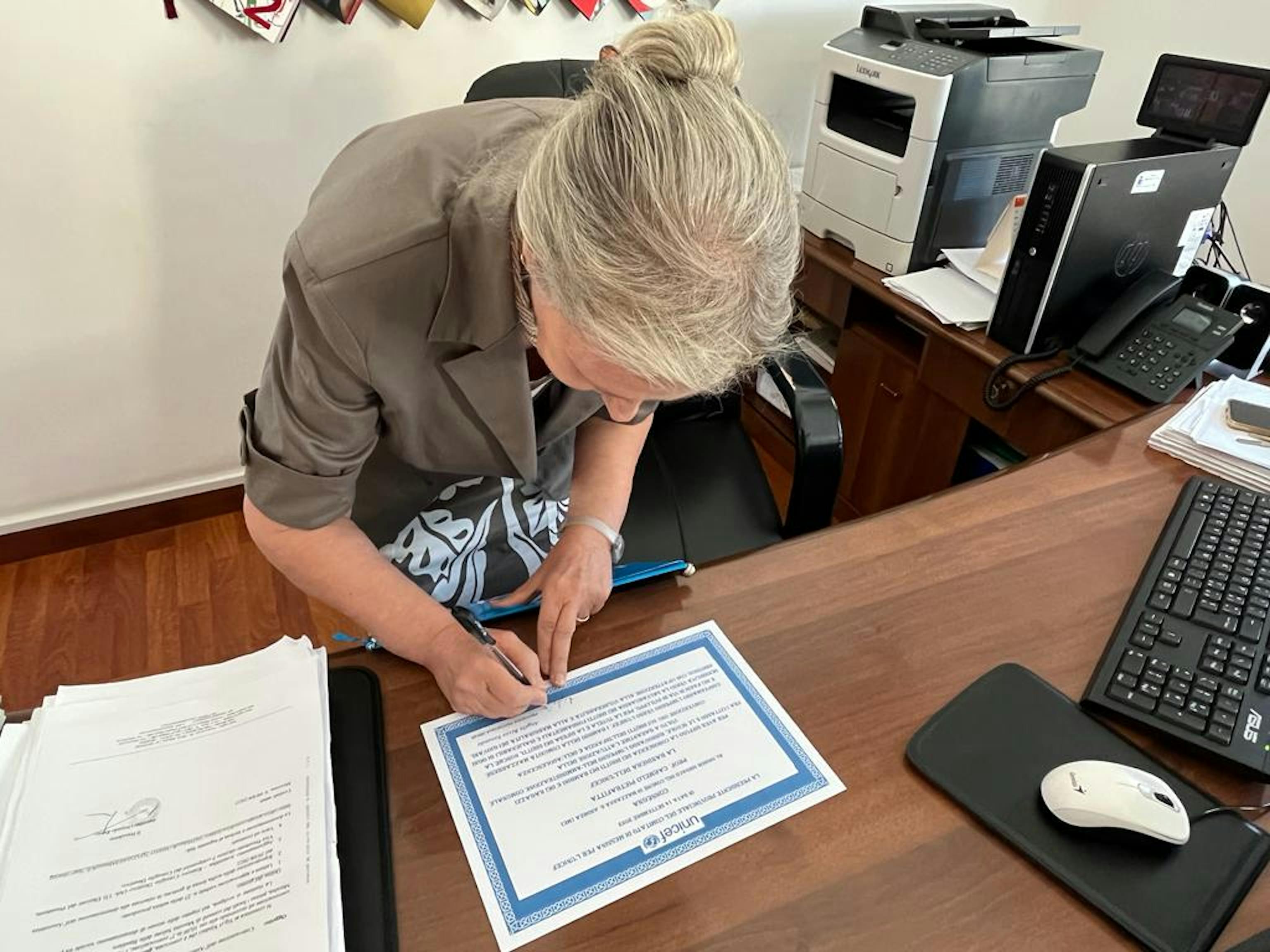 Angela Rizzo Faranda firma l'attestato con la motivazione per la consegna della bandiera UNICEF