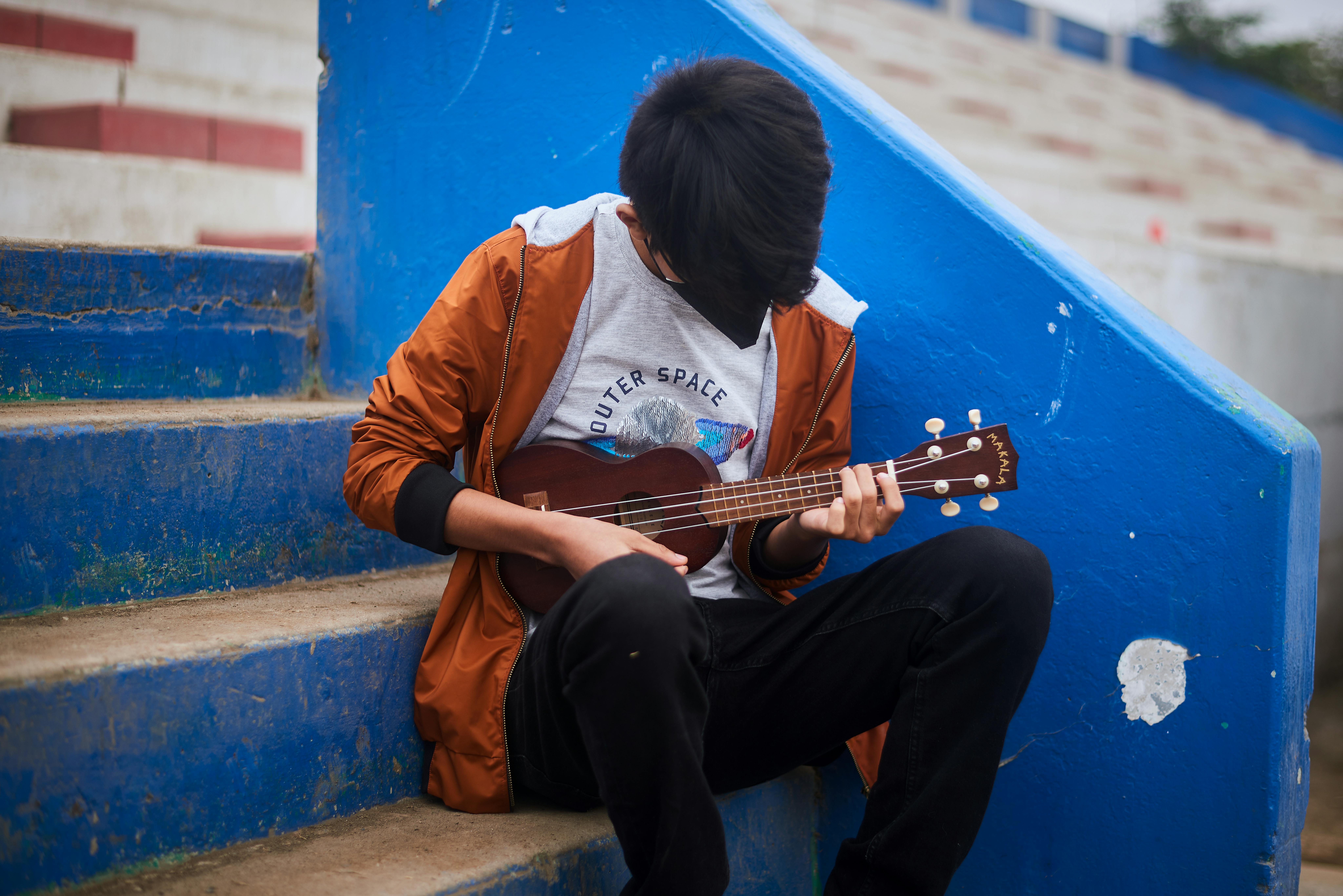 Perù: Andre, 14 anni, suona l'ukulele mentre aspetta sui gradini dello stadio di Carabayllo, un distretto a Nord di Lima, di recarsi all'appuntamento nel Centro Comunitario di Salute Mentale