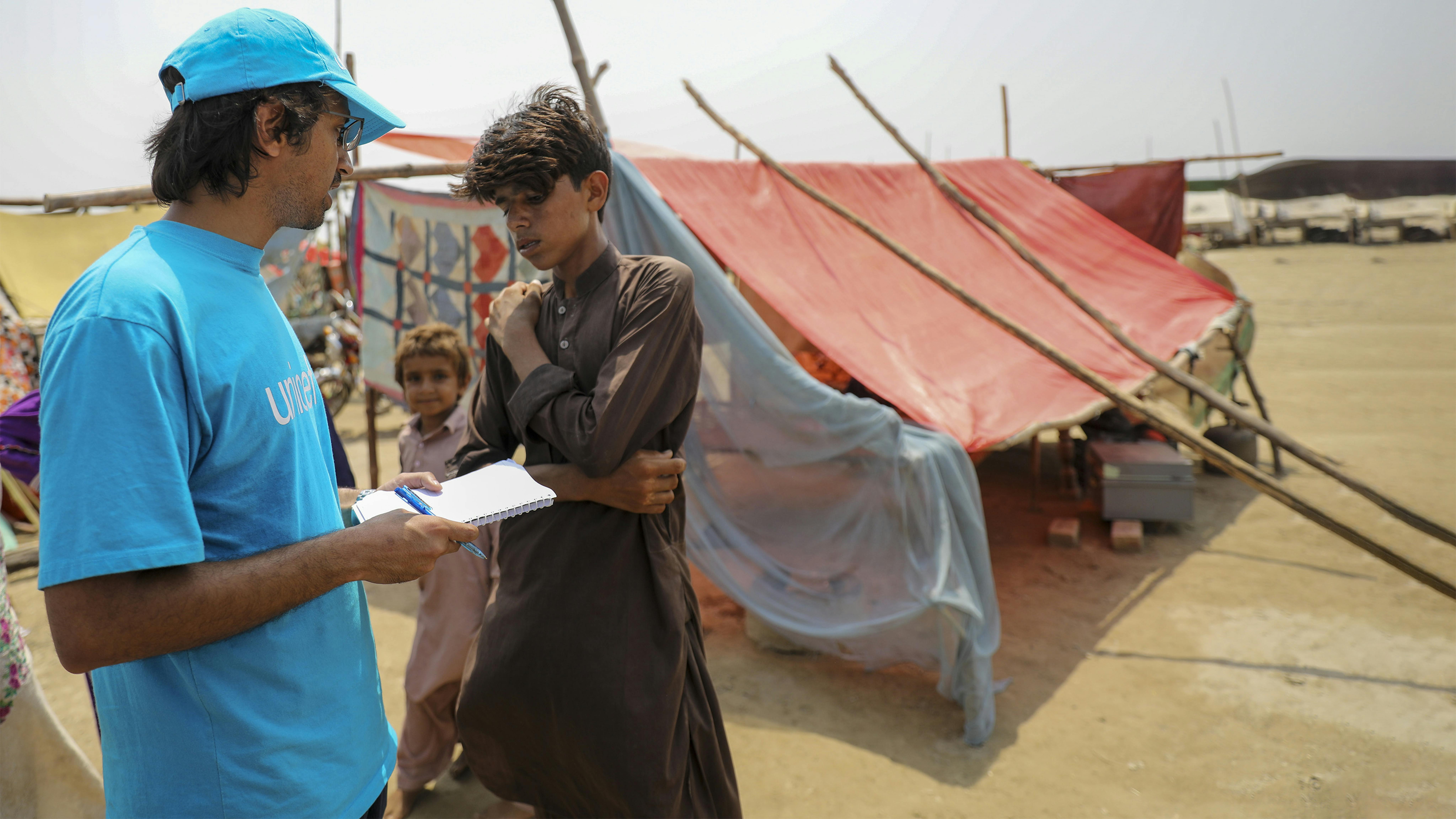 Pakistan, un operatore dell'UNICEF parla con Yasir, 14 anni, un ragazzo che vive in un campeggio allestito dal governo nel distretto di Khairpur