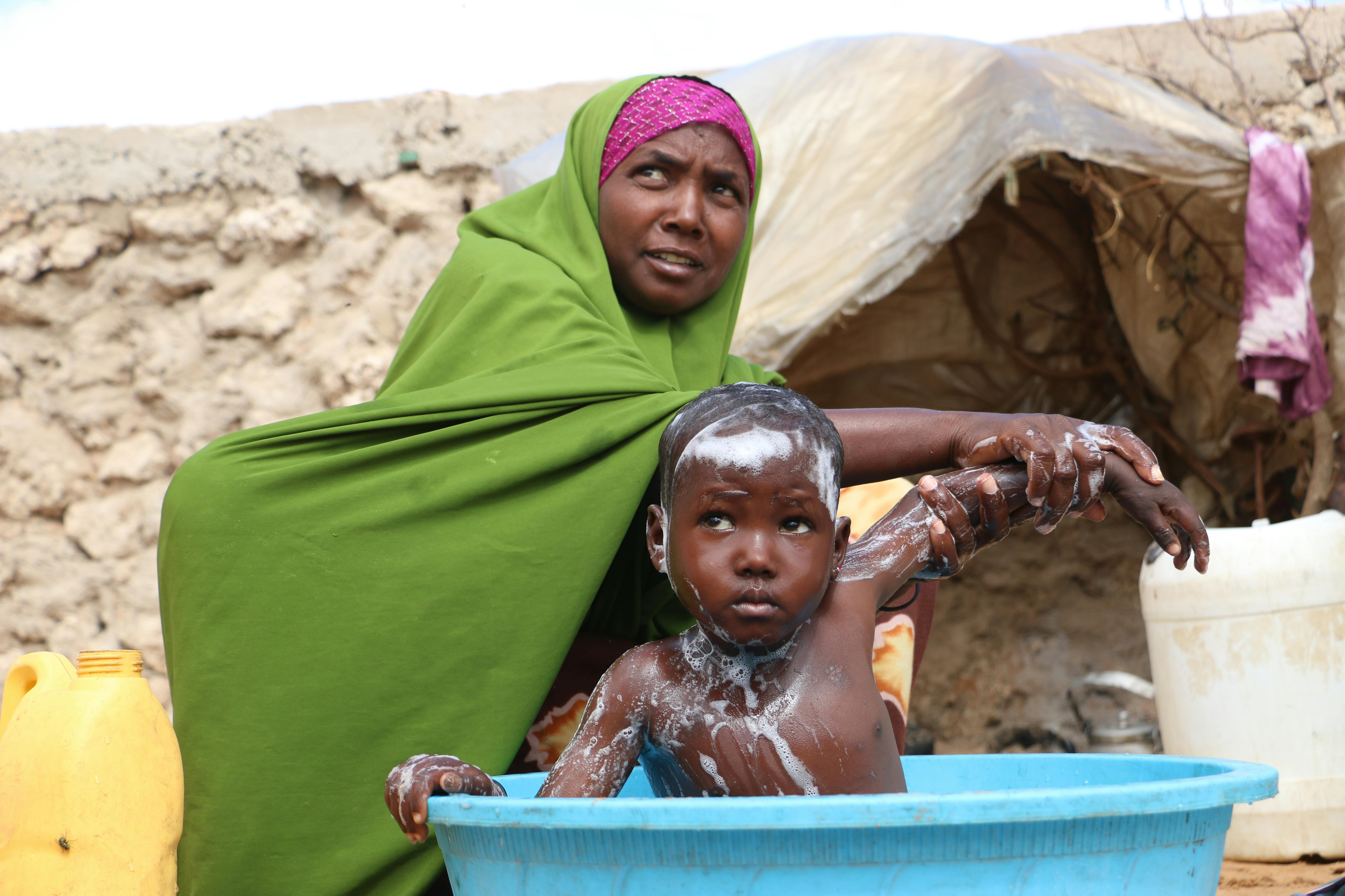 Khadijo fa il bagnetto alla sua bambina di 5 anni, Fatima nel campo Gurman per sfollati, alla periferia di Mogadiscio, Somalia.