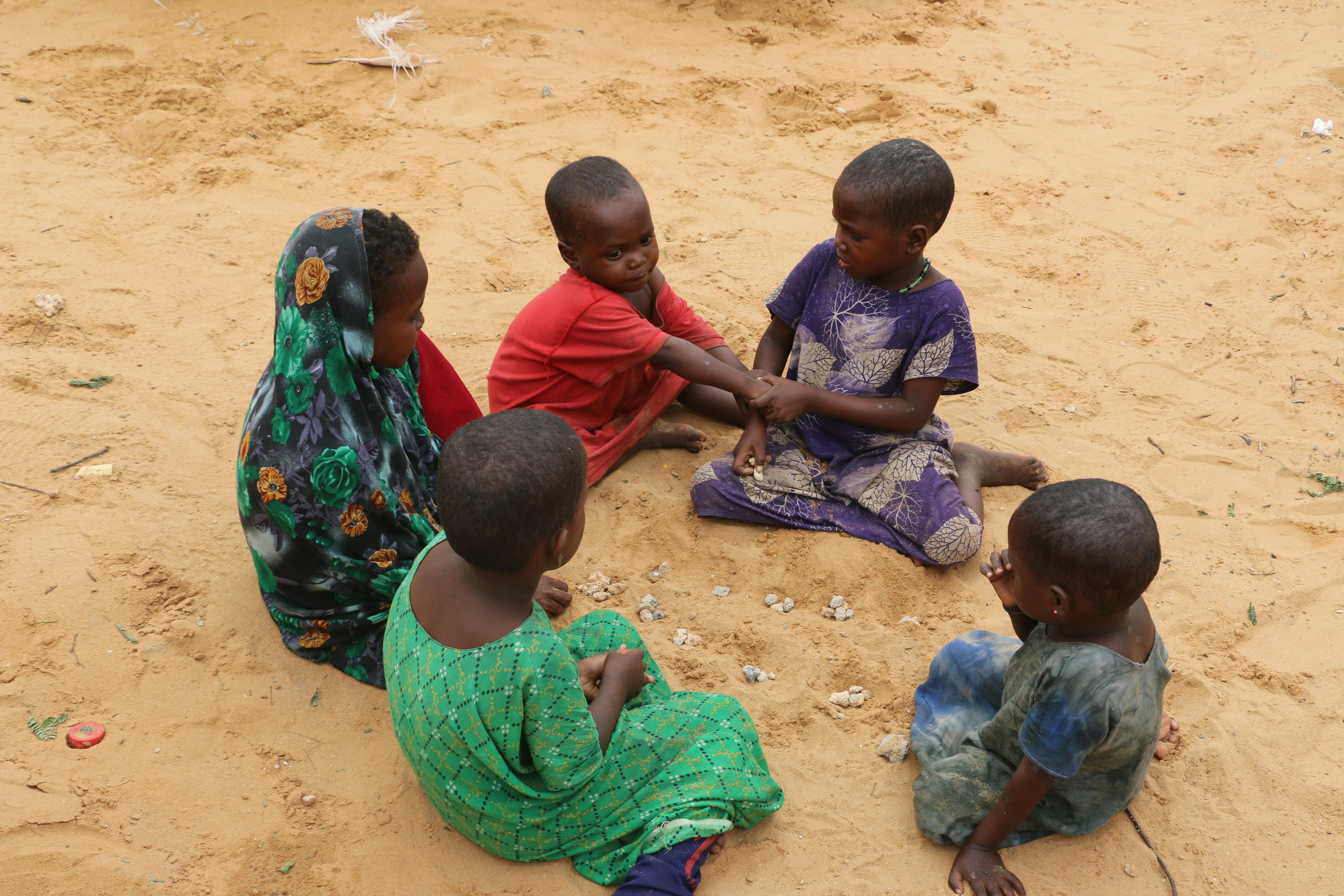 Un gruppo di bambini gioca con sabbia e pietre davanti al loro rifugio improvvisato nel campo per sfollati interni di Gurman, alla periferia di Mogadiscio, in Somalia.