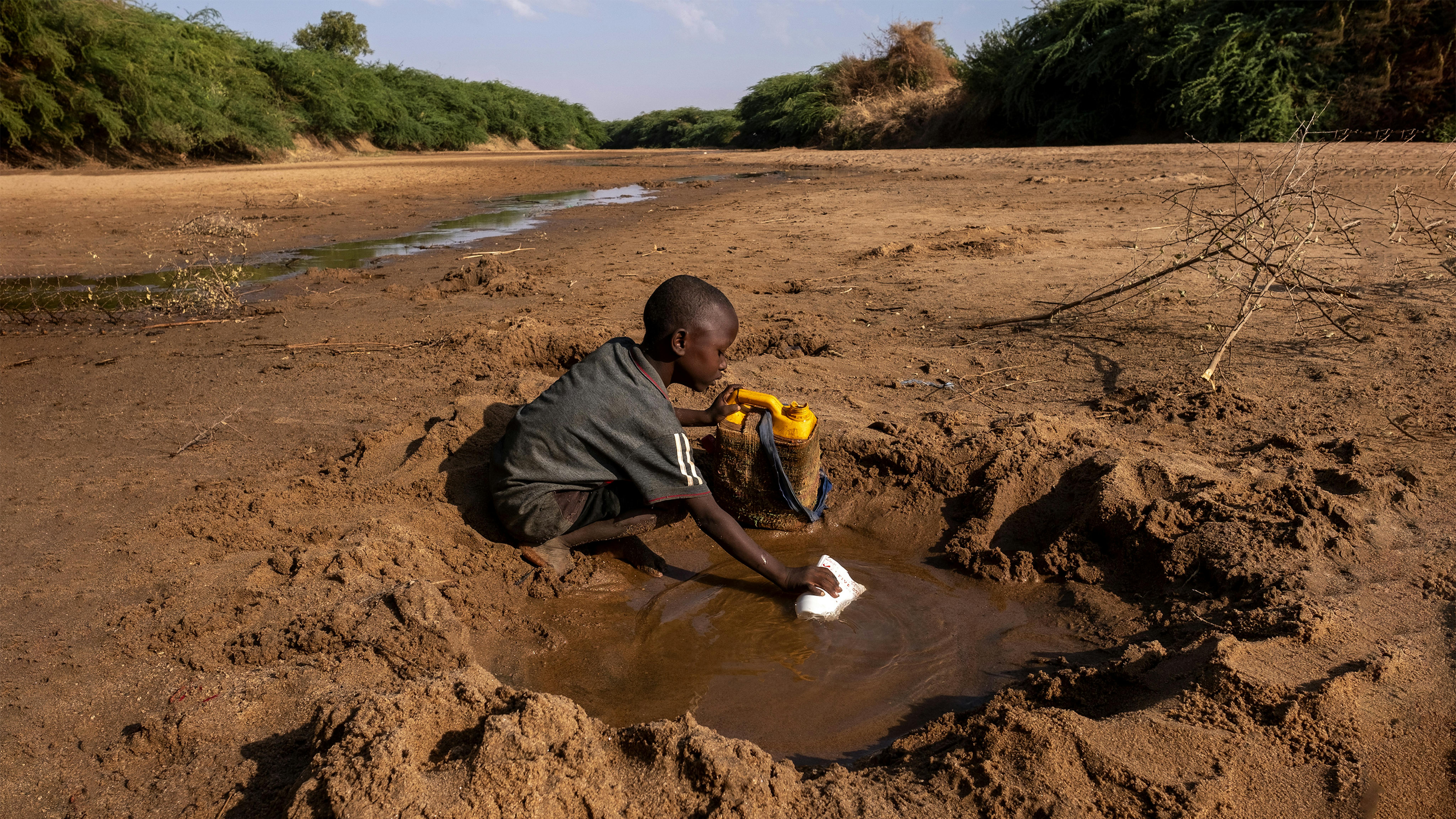 Somalia - Un giovane ragazzo raccoglie quella poca acqua che può da un fiume prosciugato a causa di una grave siccità
