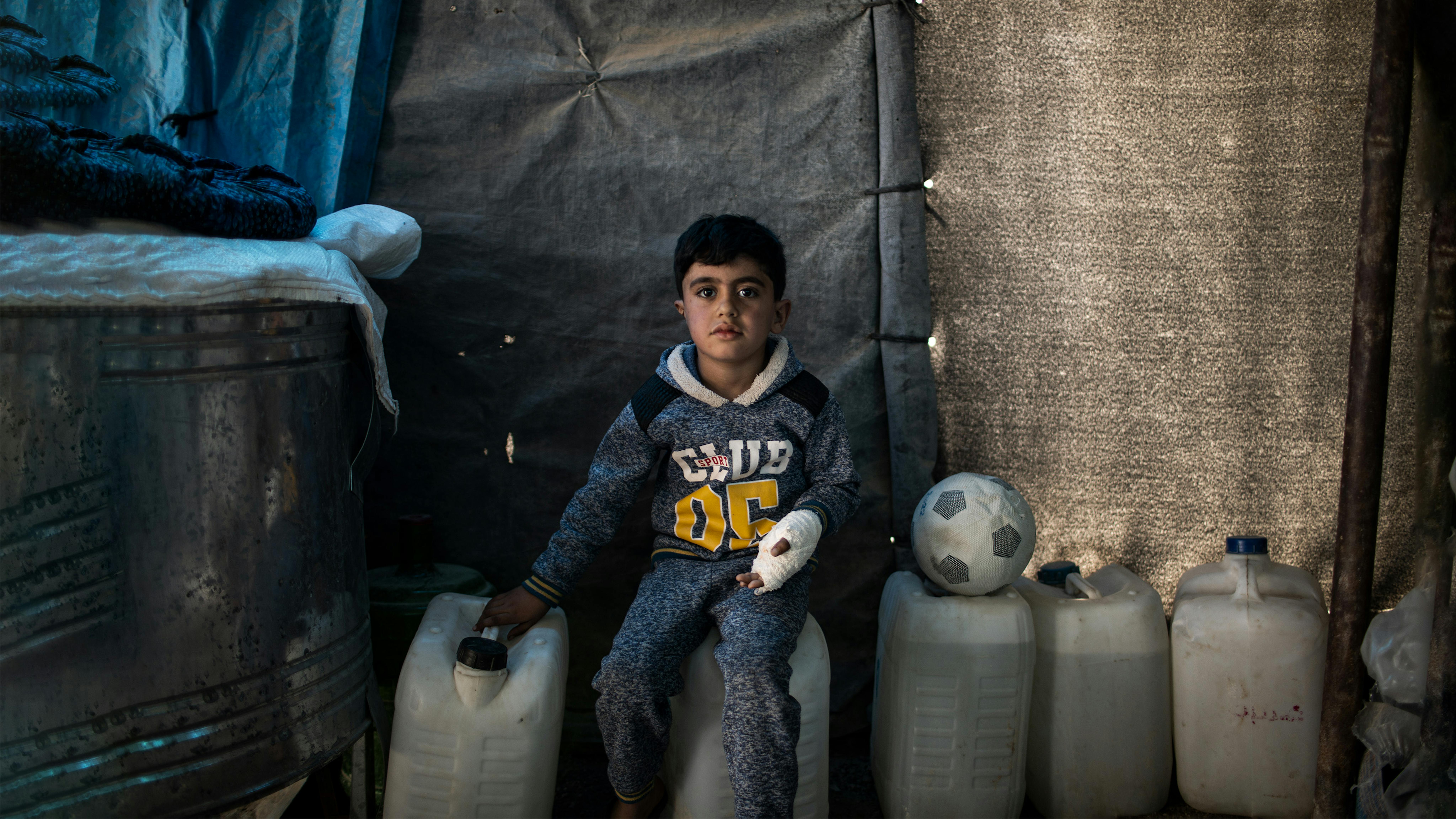 Iraq, Hussein, 5 anni, siede su un contenitore d'acqua nella sua casa temporanea ad Habaniya, alla periferia di Fallujah.