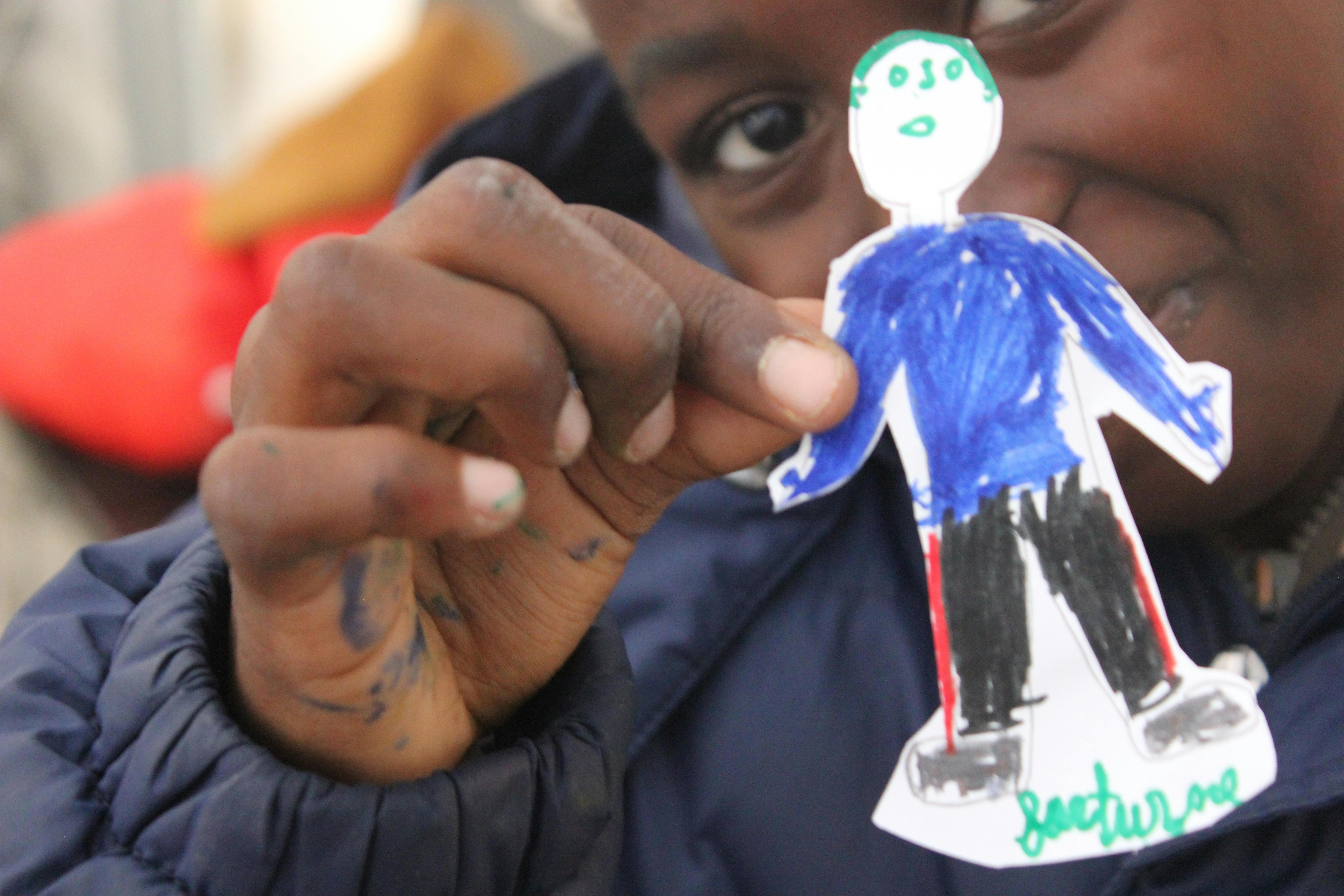 Hope, bambina camerunense di 8 anni, mostra il disegno realizzato per il Safe Space