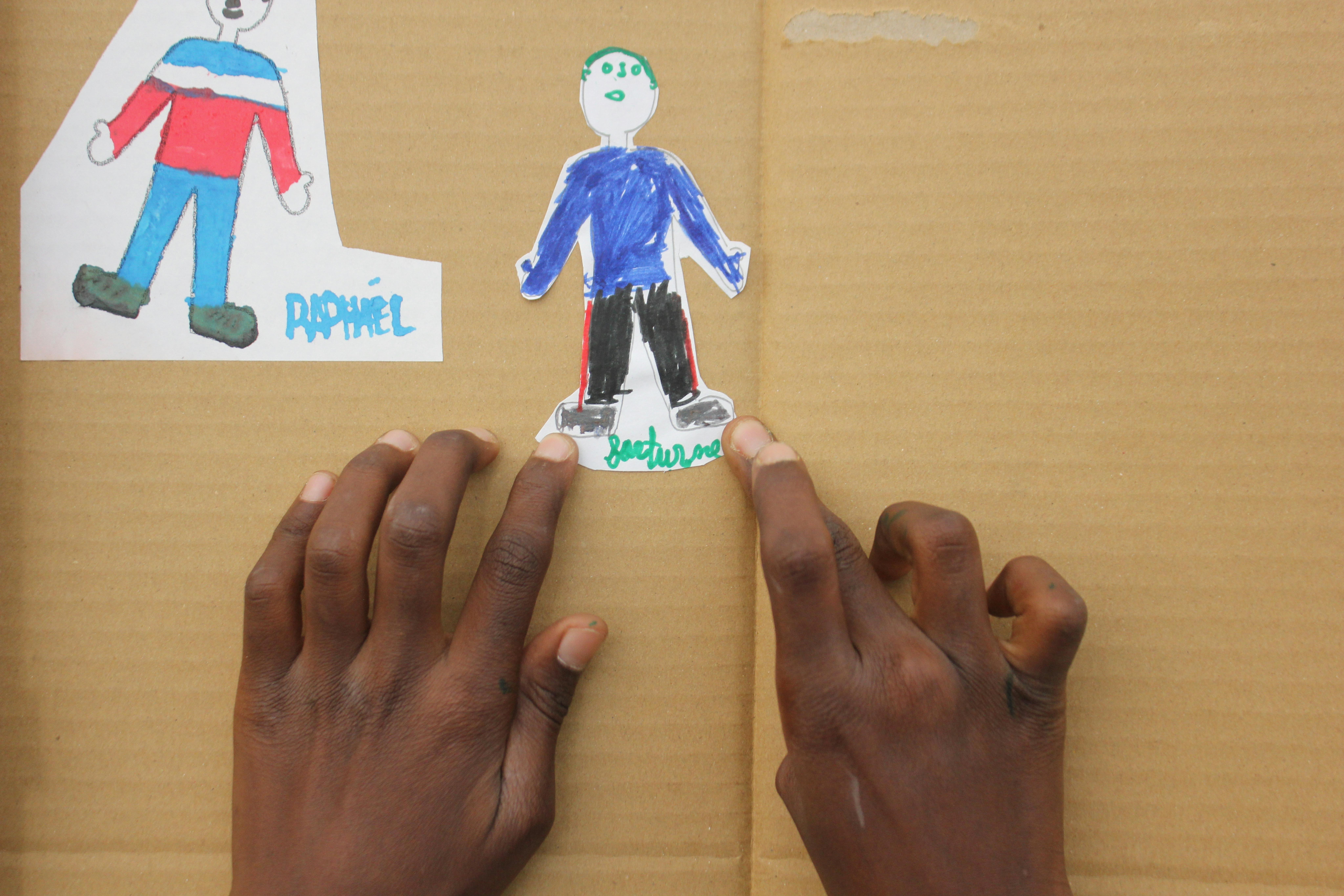 Hope, bambina camerunense di 8 anni, mostra il disegno realizzato per il Safe Space