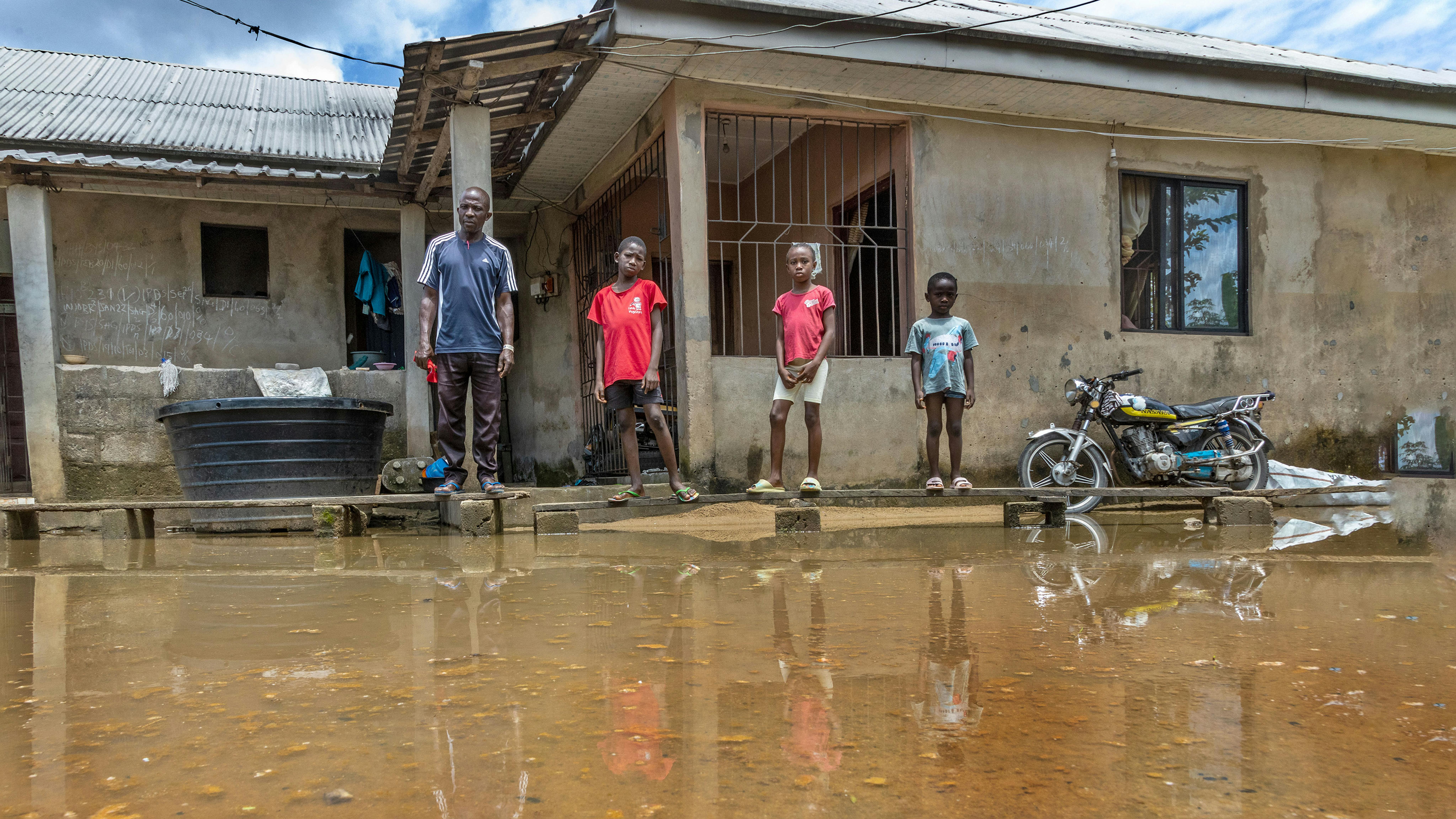 Nigeria - kpoebi Germany 45 anni, con i suoi figli Peretimifa Germany, Samuel Germany e Joy Germany sono in piedi sulla passerella di legno improvvisata davanti alla sua casa colpita dall'alluvione a Sagbama,
