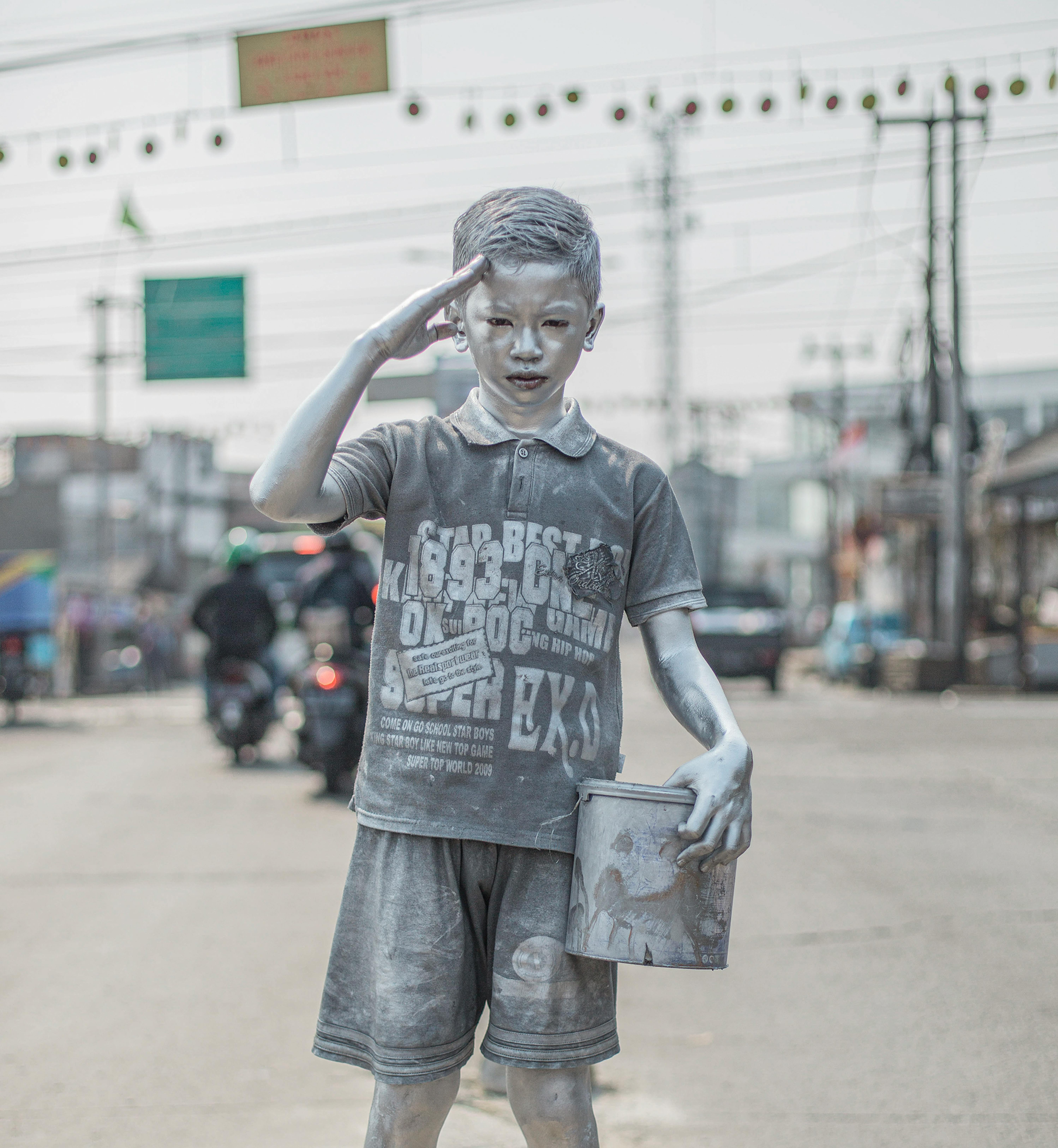 © Agoes Rudianto, Indonesia, GEOlino -Il popolo d'argento: Rifki Firmansyah, dodici anni, si dipinge con vernice argentata al mattino e poi si esibisce agli incroci stradali come un piccolo robot umano fino al pomeriggio per aiutare la sua famiglia