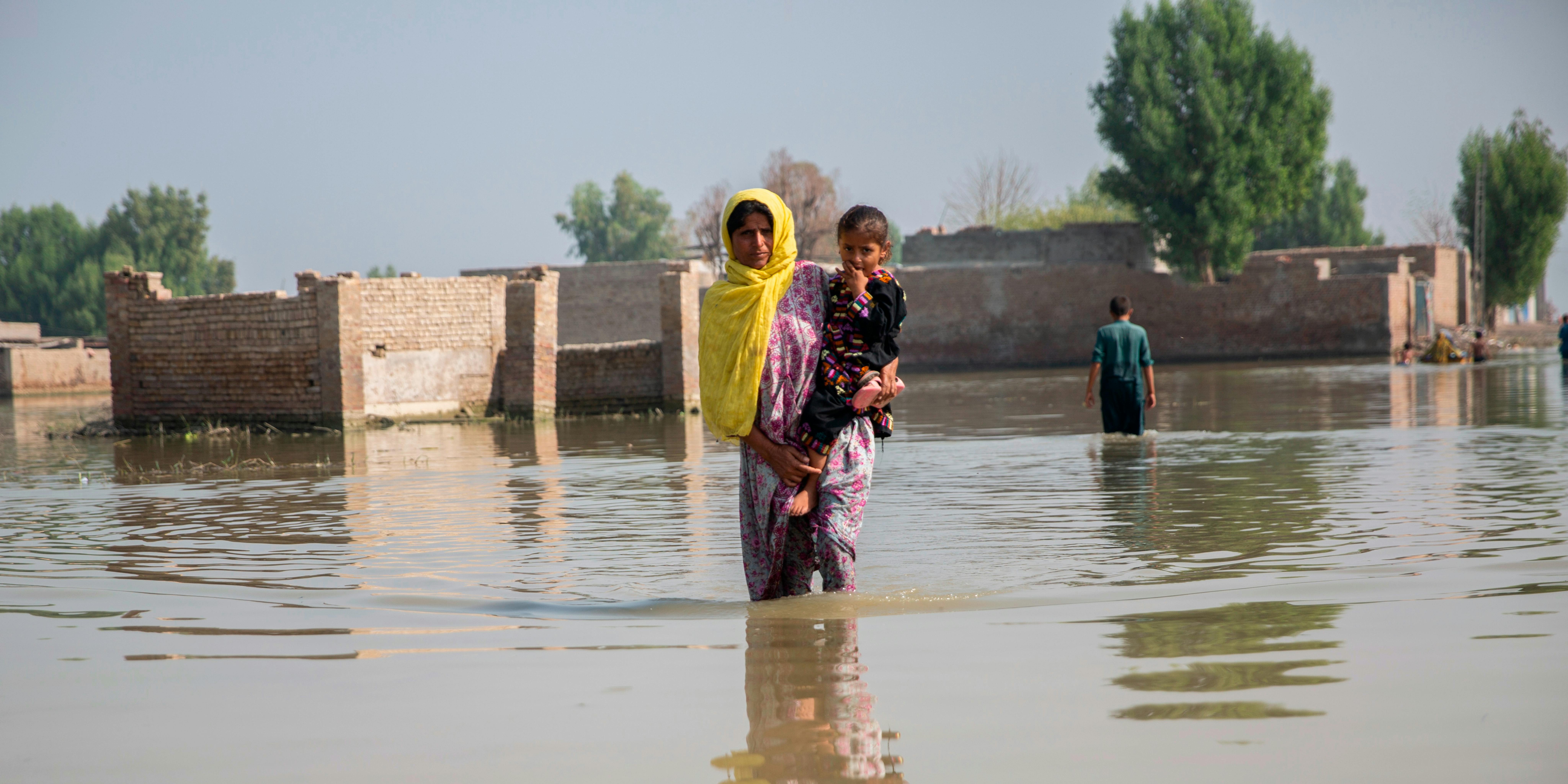 Pakistan - Una donna tiene in braccio sua figlia mentre si trova nelle acque alluvionali nella provincia del Sindh