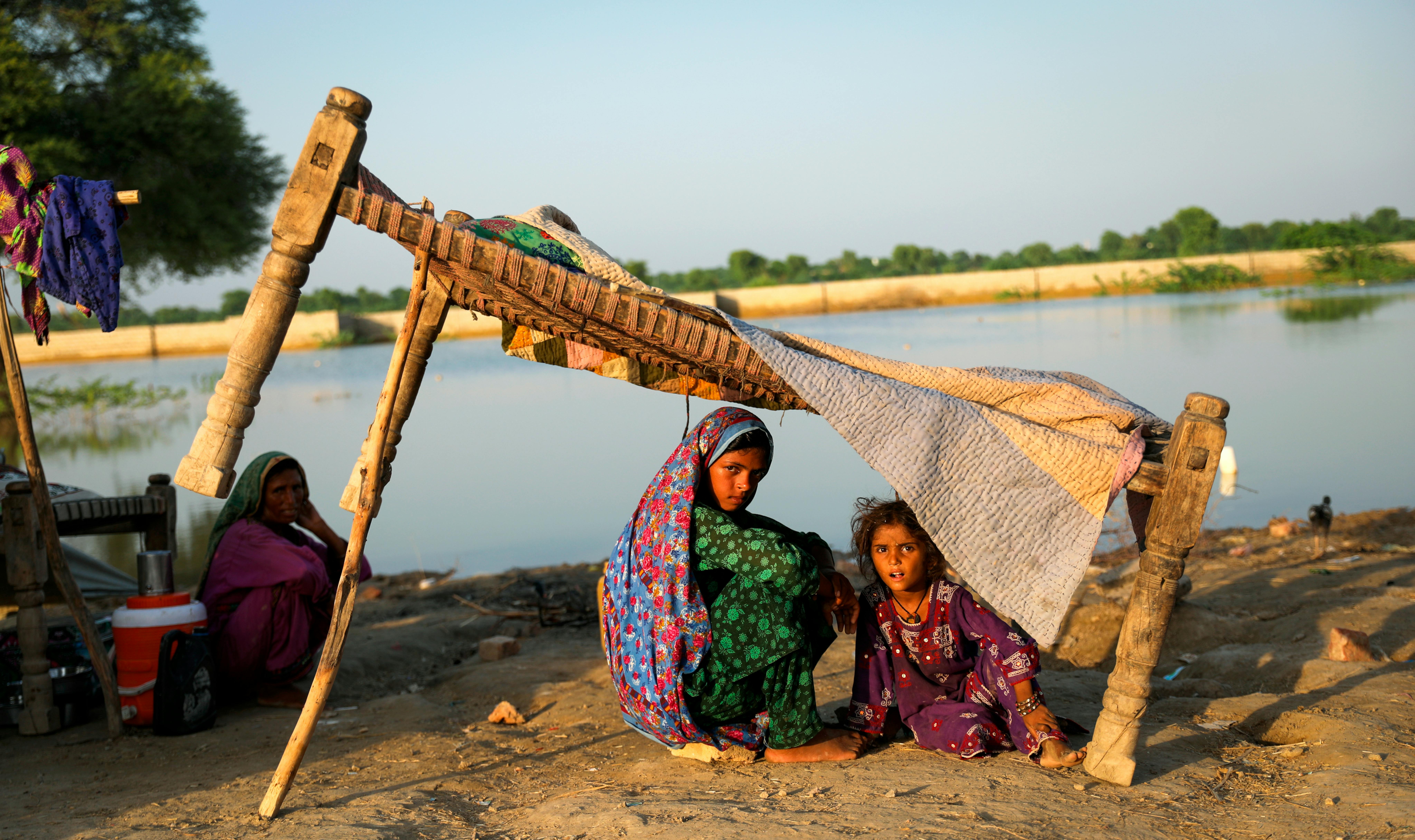 Pakistan, Bahira, 11, Fozia, 5, e la loro madre Rukhsar siedono accanto alle acque alluvionali sul ciglio della strada nel distretto di Jacobabad, provincia di Sindh