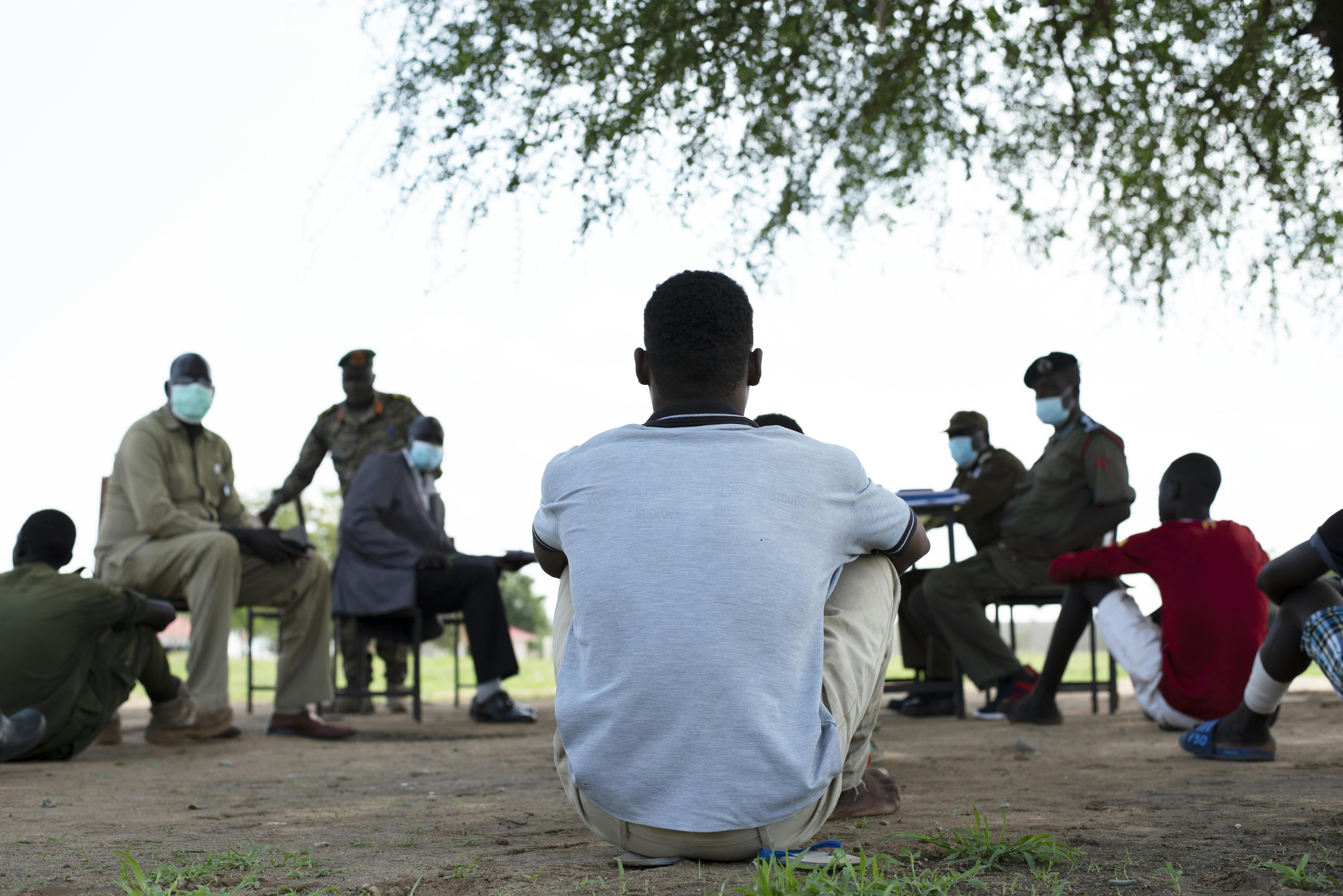 Ragazzi associati alle forze armate sono in attesa di essere liberati, mentre sullo sfondo sono in corso le trattative tra rappresentanti dell'UNICEF, della Missione delle Nazioni Unite in Sud Sudan (UNMISS) e della Commissione nazionale per il disarmo e la smobilitazione e le Forze di difesa popolare del Sud Sudan (SSPDF)