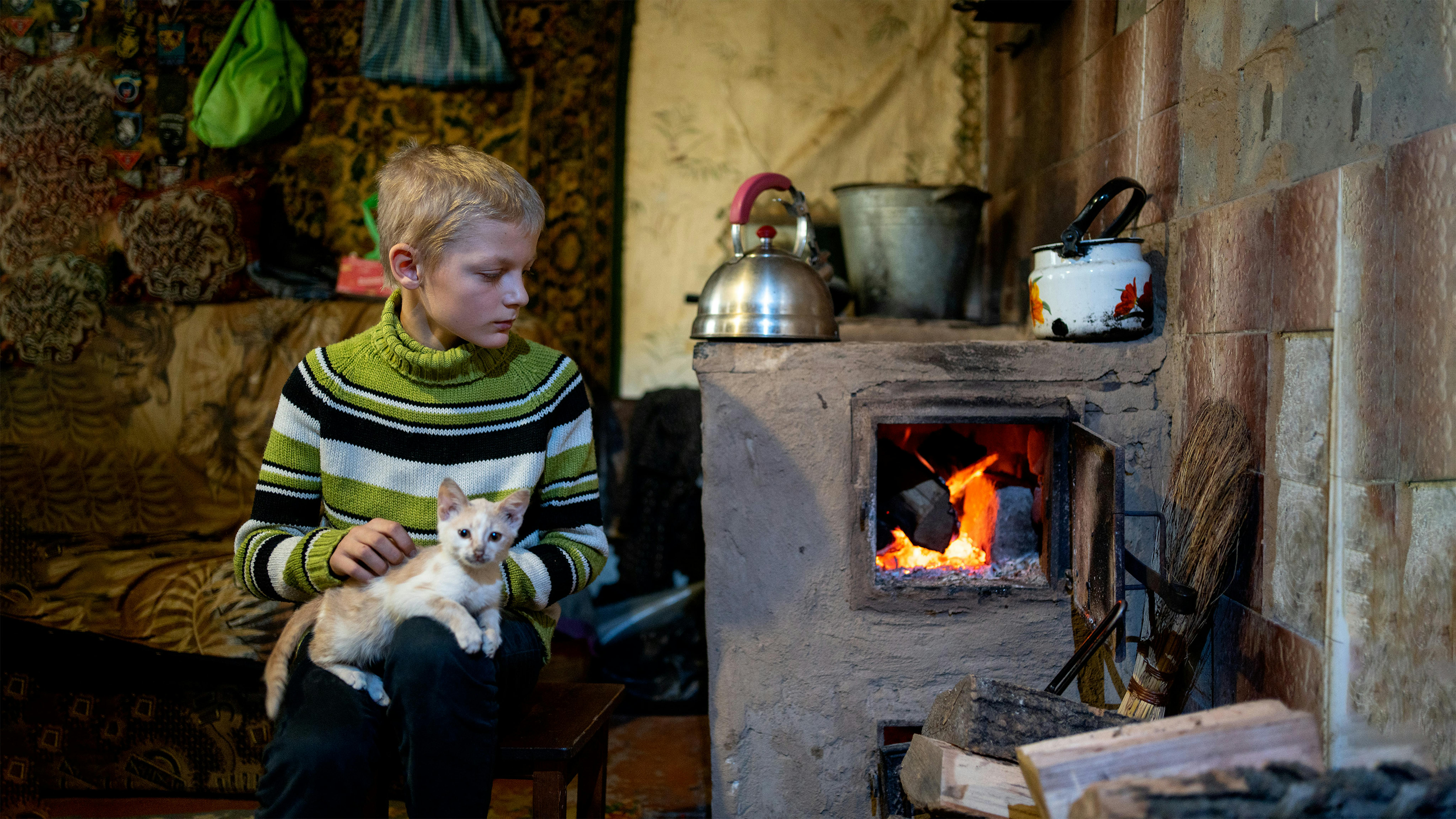 Bohdan, di  15 anni con il suo gatto, prova a scaldarsi vicino al forno a legna nella sua casa  dove vive con la nonna e due sorelle a Izyum