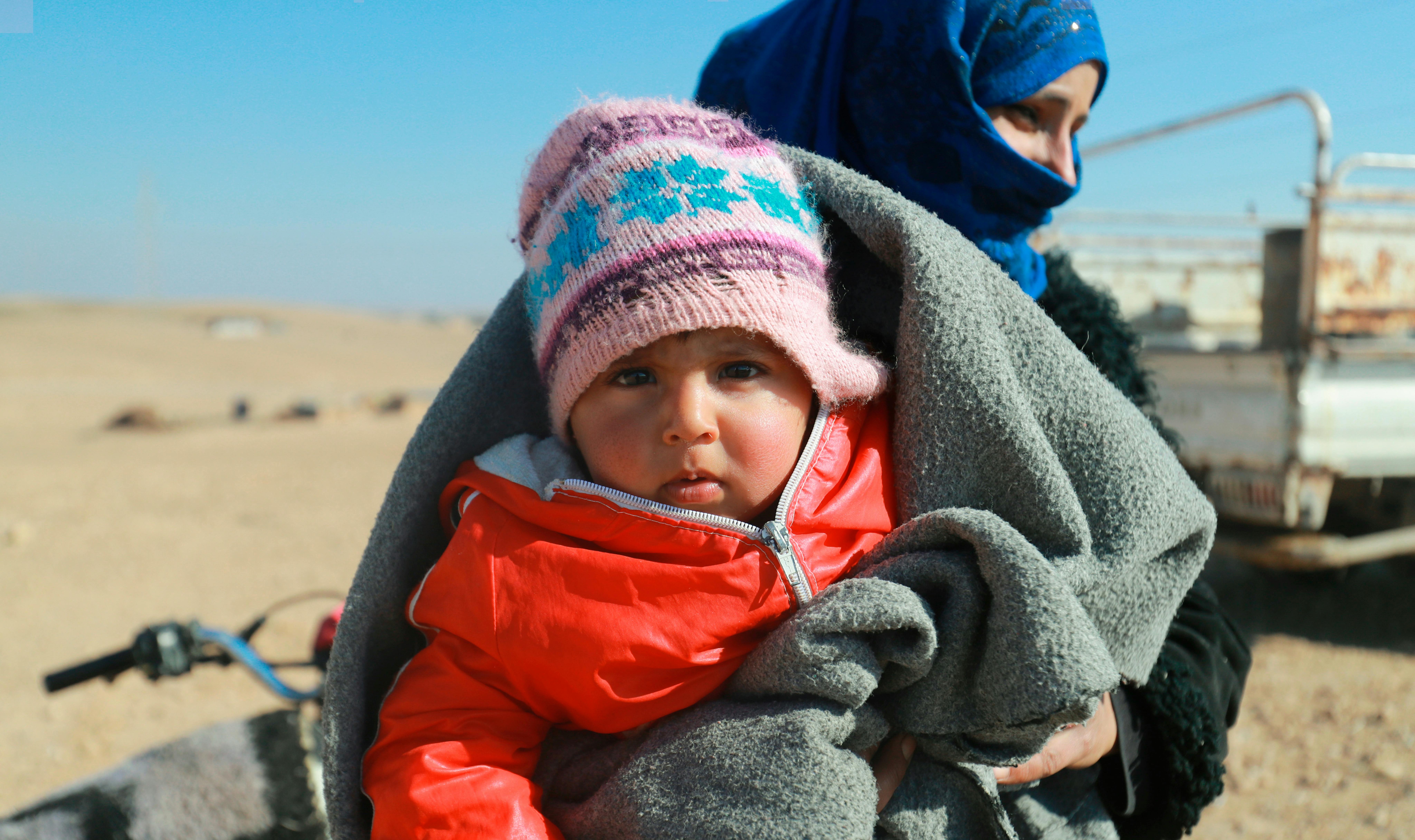 Questa bambina guarda dritta in camera mentre sua madre aspetta di ricevere il kit invernale distribuito dall'UNICEF, nell'insediamento informale di Salhabiya, nella zona rurale orientale di Raqqa, nel nord-est della Siria, il 13 febbraio 2022.