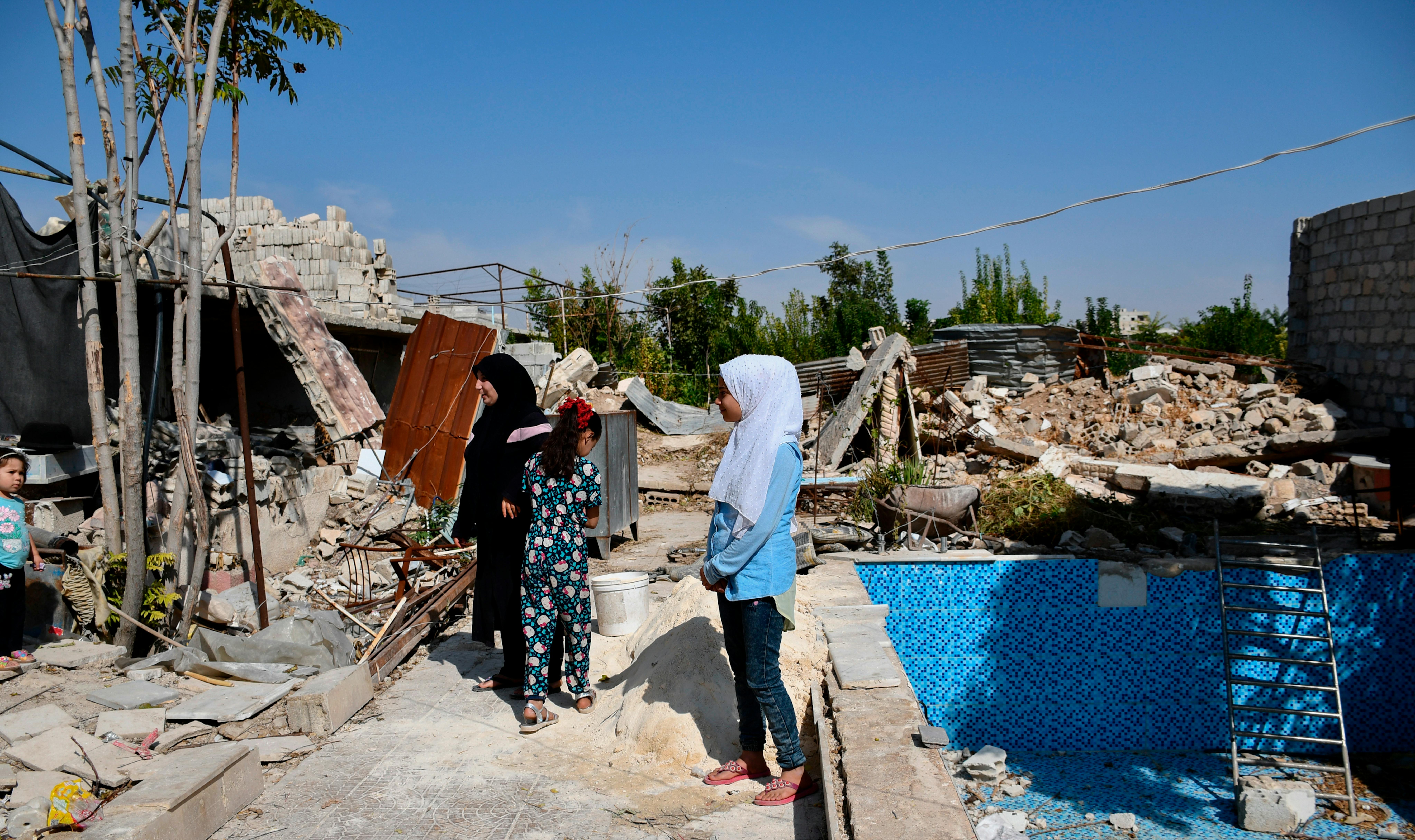 Zahira, 35 anni, e le sue figlie Hala, 14, e Reem, 11, osservano i lavori di costruzione in corso nel loro cortile a Ein Tarma, Damasco rurale, Siria,
