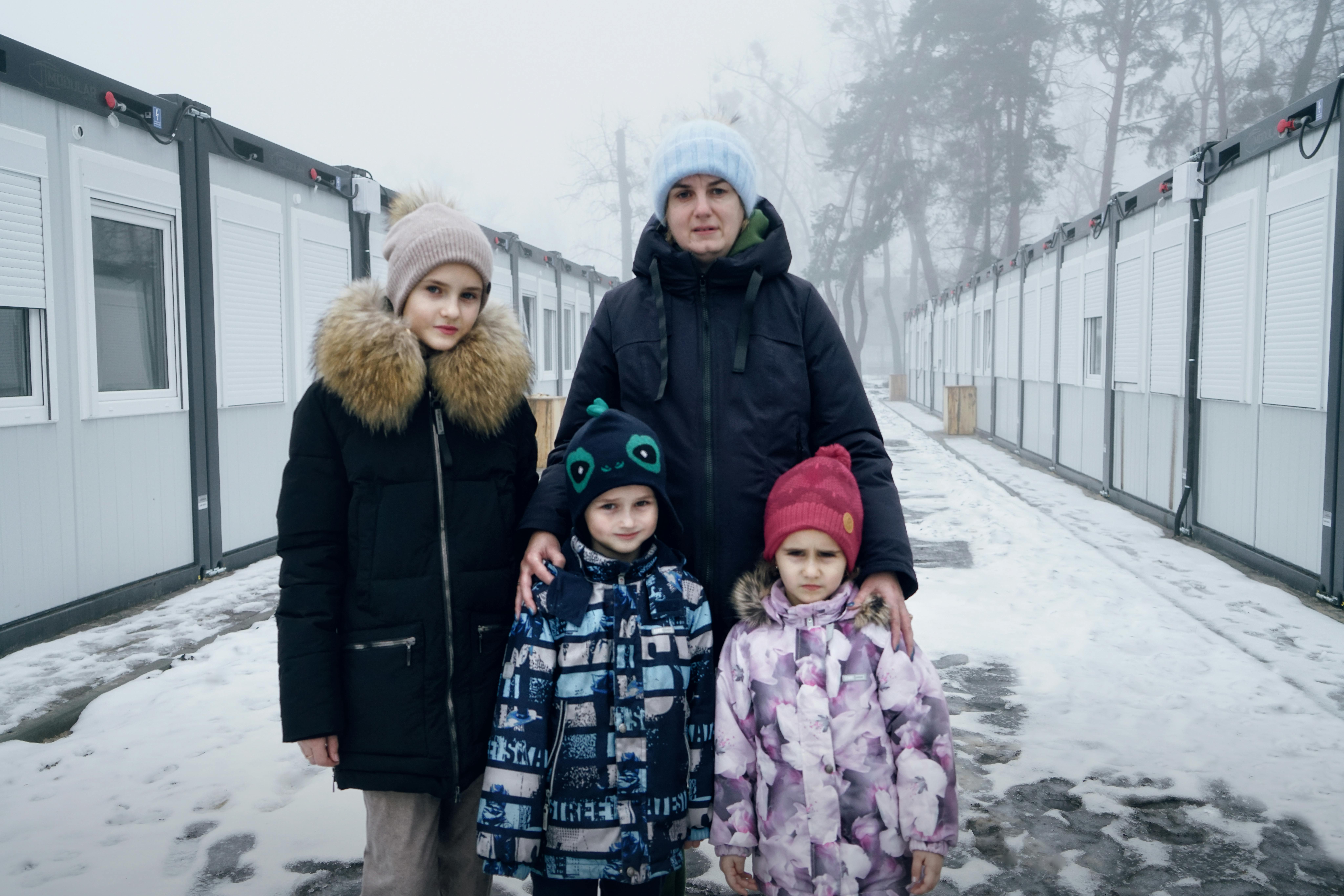 Una famiglia nella neve, fuori dell’alloggio temporaneo dove si sono rifugiati, ad Irpin, Kiev.