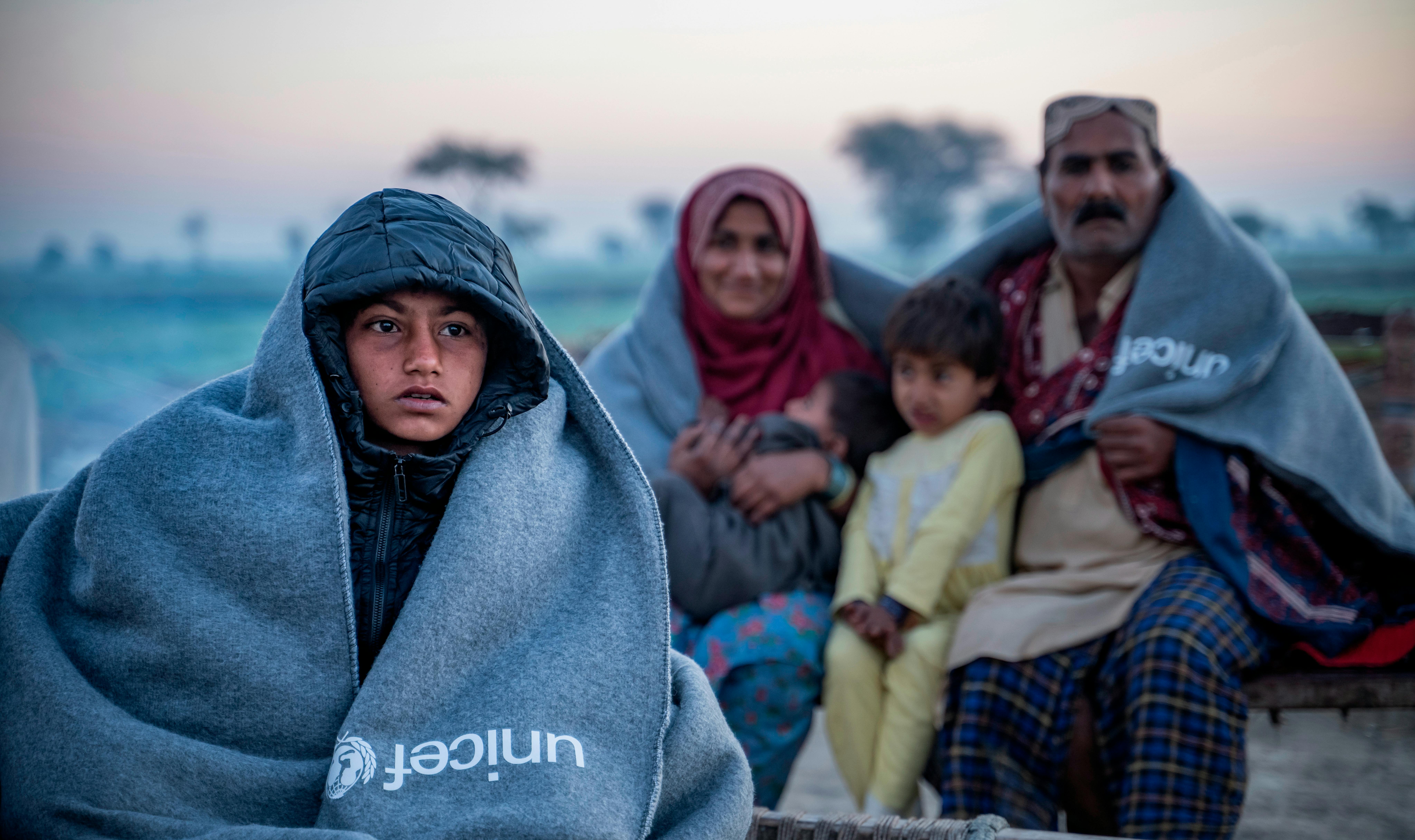 Sameer, 8 anni, e la sua famiglia siedono su un charpoy fuori casa dopo aver ricevuto il kit invernale dell'UNICEF nel villaggio di Zangi Brohi, distretto di Dadu, Sindh.