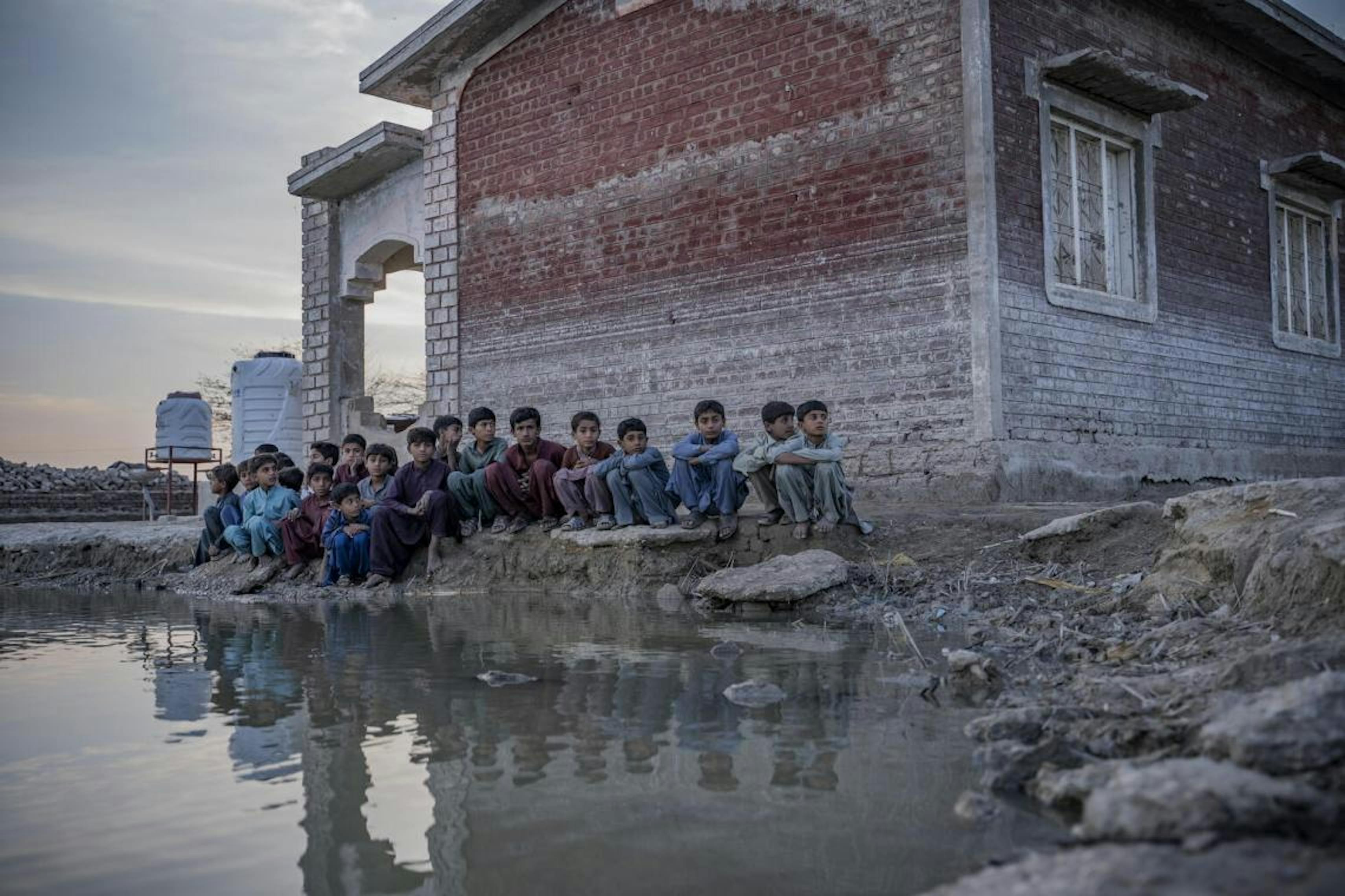 I bambini si siedono accanto alle acque alluvionali nel distretto di Dadu, nella provincia del Sindh, in Pakistan.