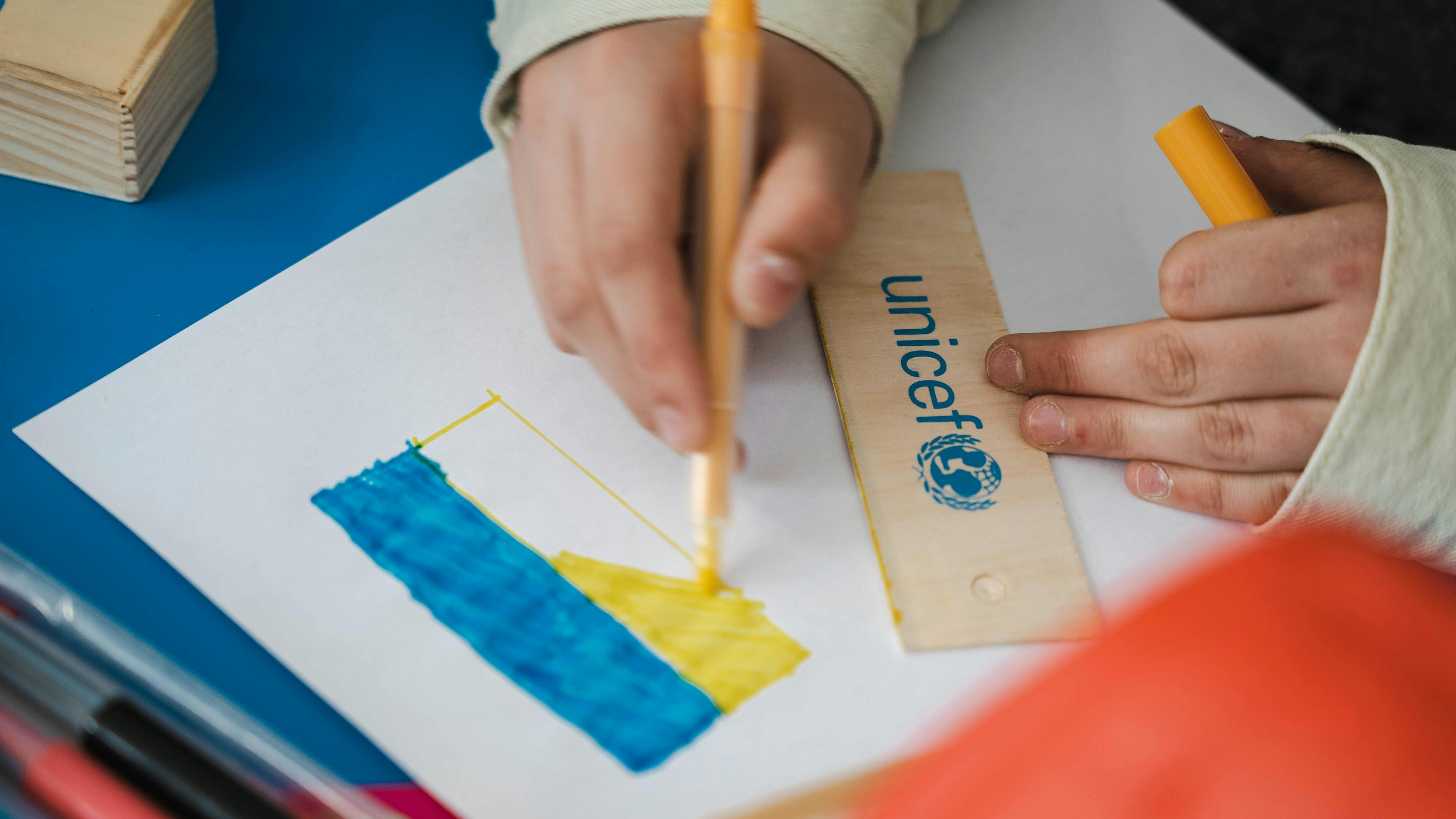 un bambino ucraino in un centro di accoglienza disegna la bandiera ucraina
