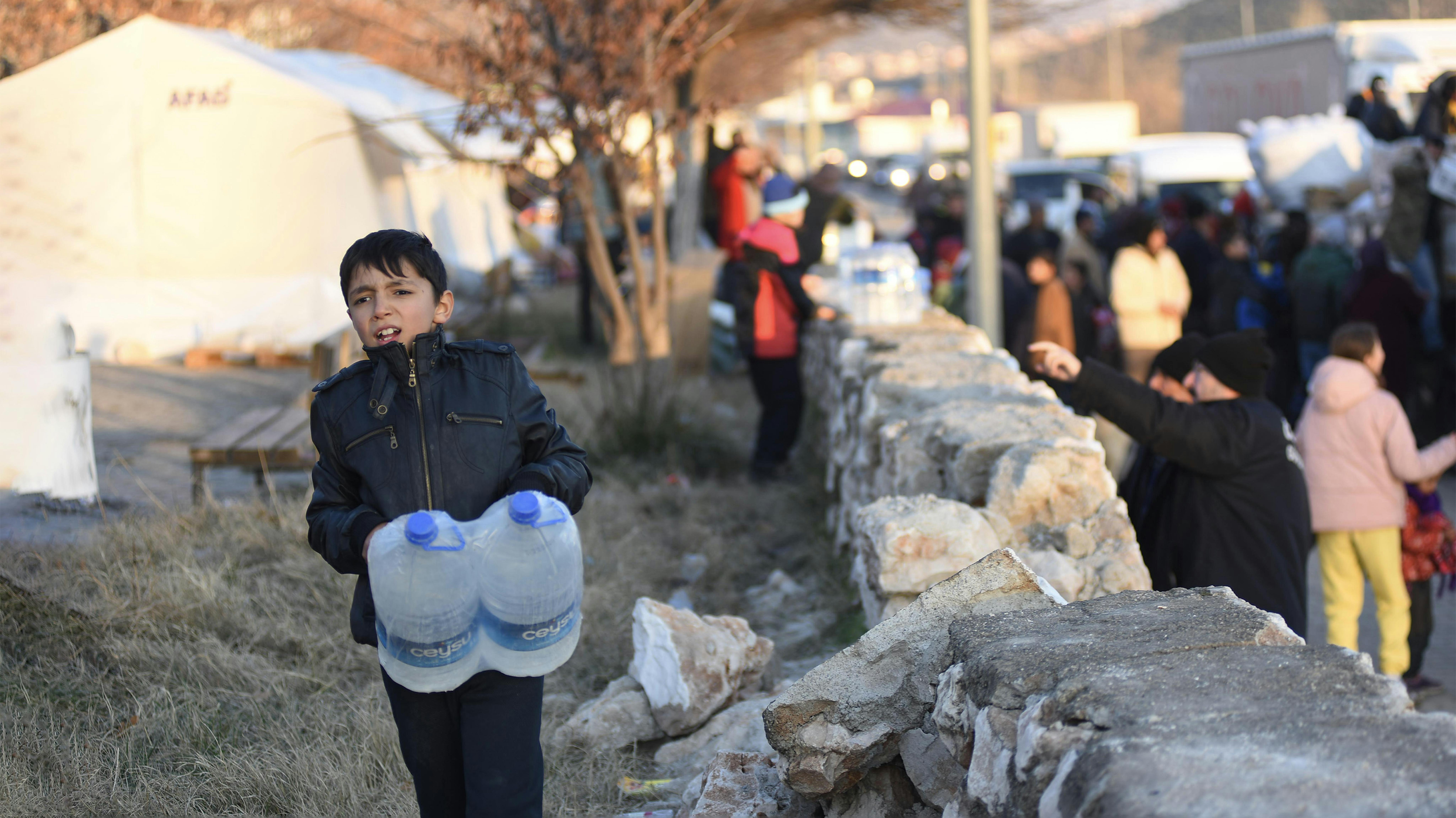 Turchia Un ragazzo trasporta pesanti bottiglie d'acqua di plastica nel rifugio temporaneo allestito per i sopravvissuti al terremoto a Kahramanmaraş,