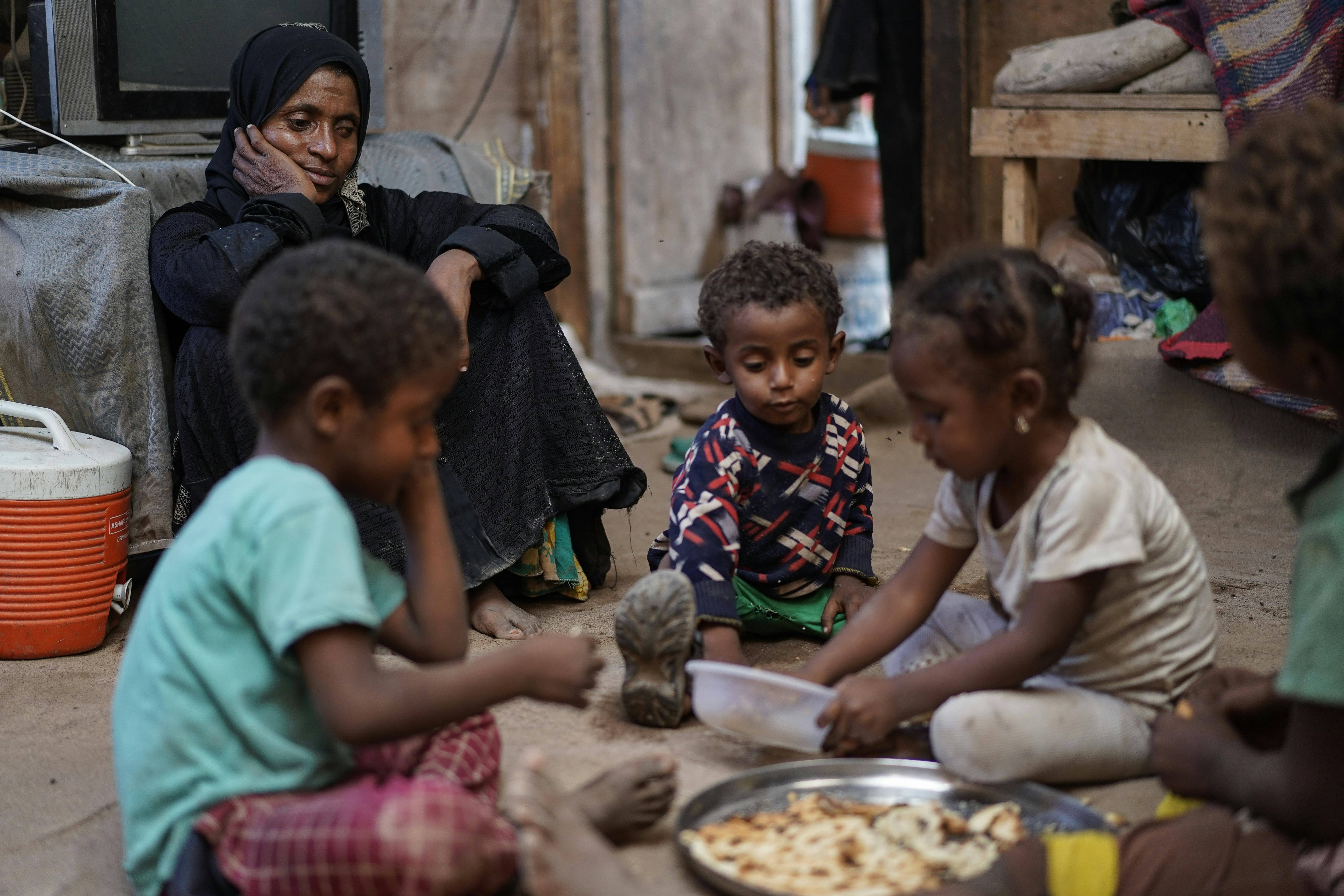 Yemen, Fatima Muhammed Saeed, 35 anni, guarda i suoi figli mangiare un pasto che ha preparato per loro. Sono sfollati a causa del conflitto in corso e lei è malnutrita: non c'è abbastanza cibo per tutti
