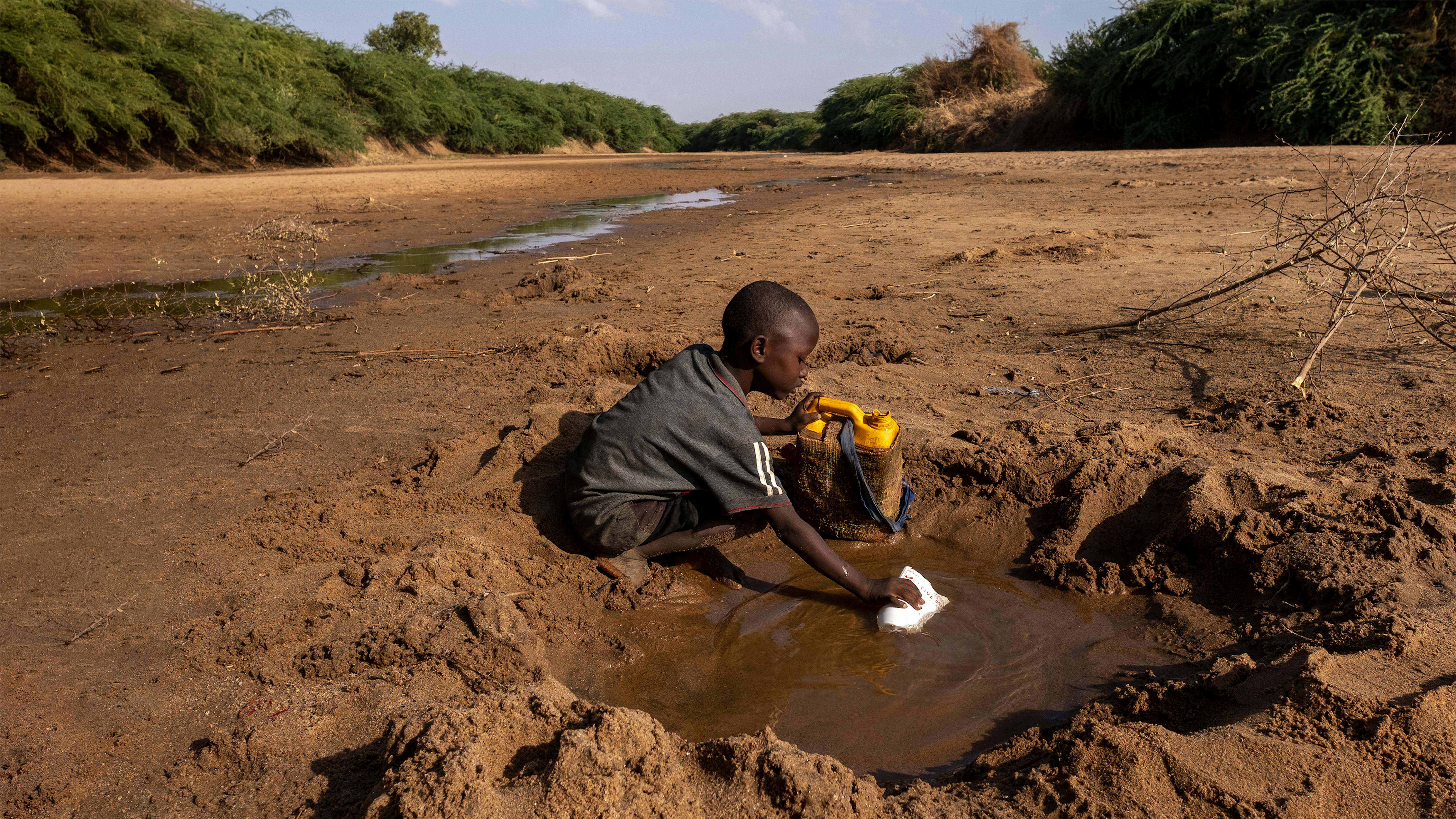 Somalia - Un ragazzino raccoglie la poca acqua che può da un fiume prosciugato a causa di una grave siccità.