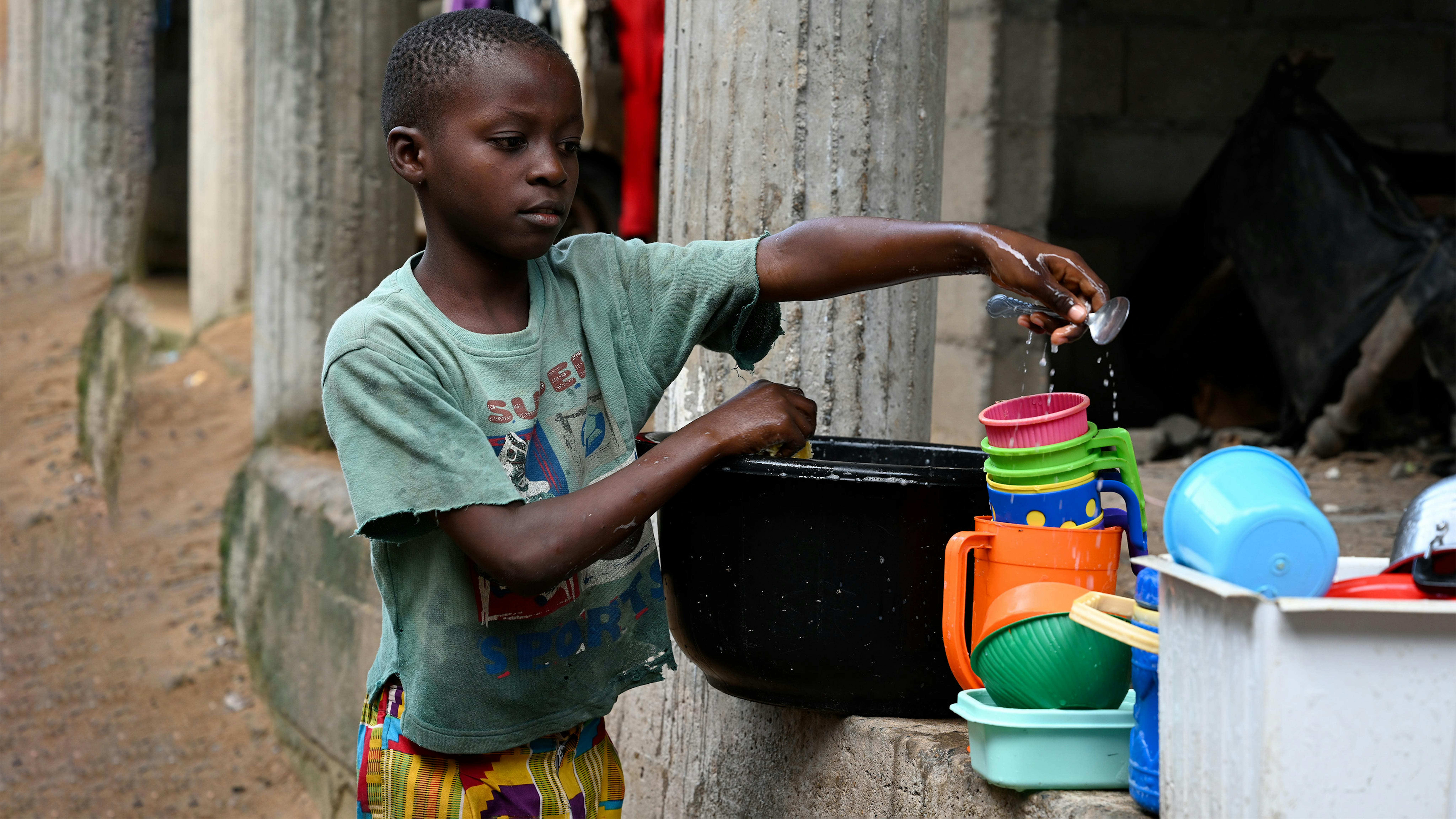Camerun - Un bambino che lava i piatti per le strade di Douala