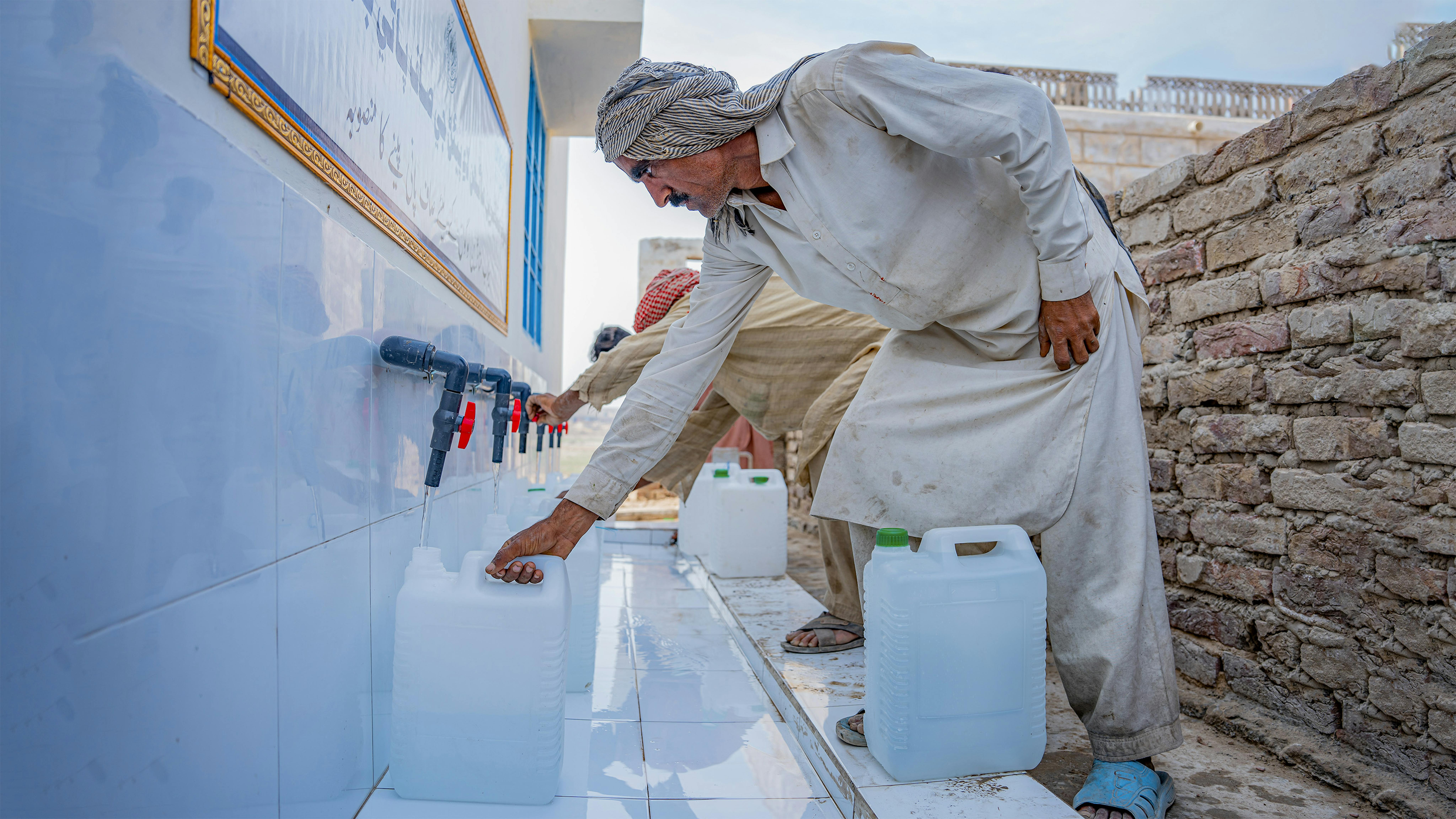 Pakistan - La gente del posto riempie l'acqua in un impianto di filtrazione dell'acqua installato dall'UNICEF con l'assistenza finanziaria del governo del Regno Unito.