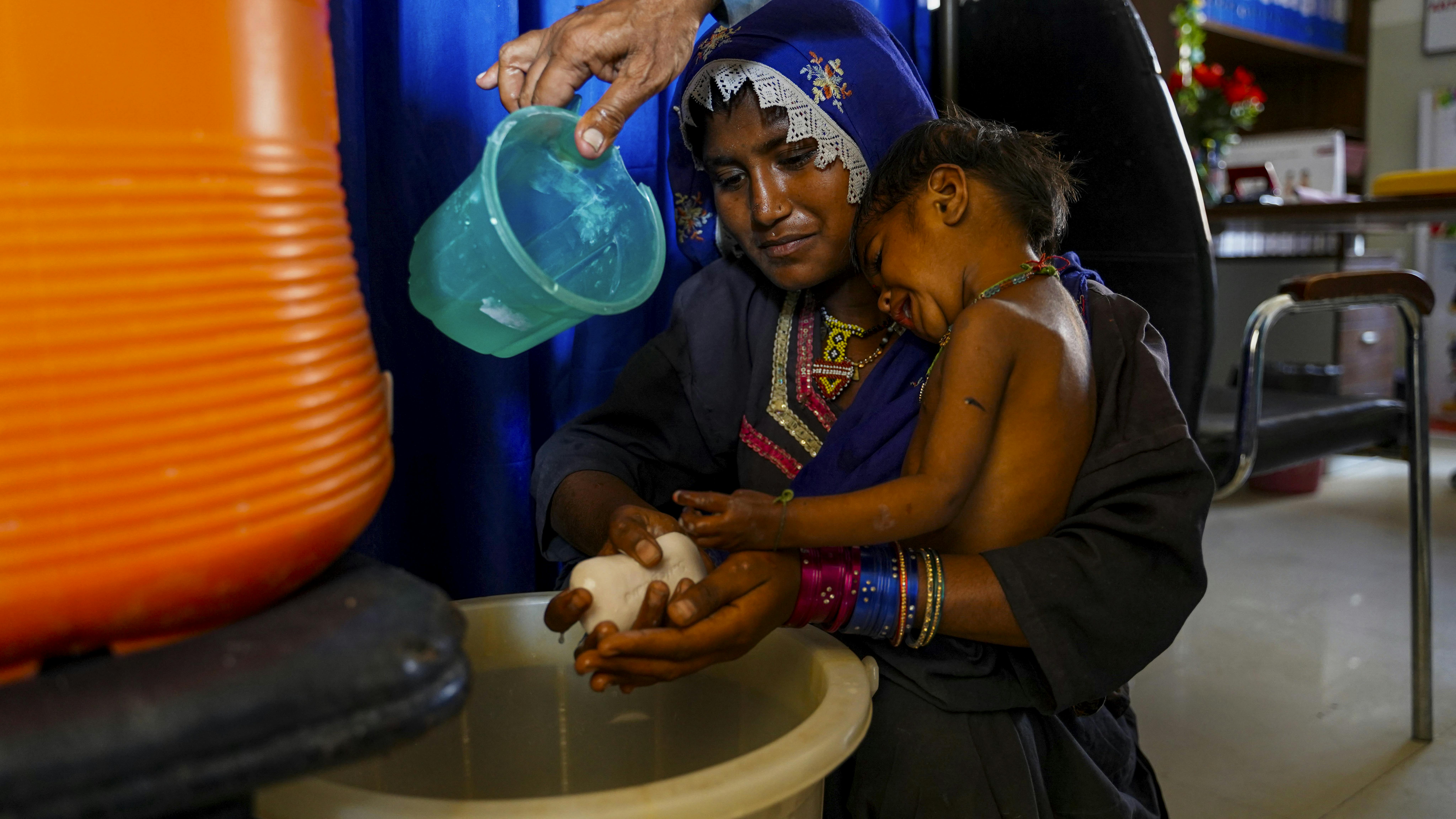 Pakistan - Un operatore sanitario aiuta una madre a lavarsi le mani con il sapone in una clinica sanitaria supportata dall'UNICEF.