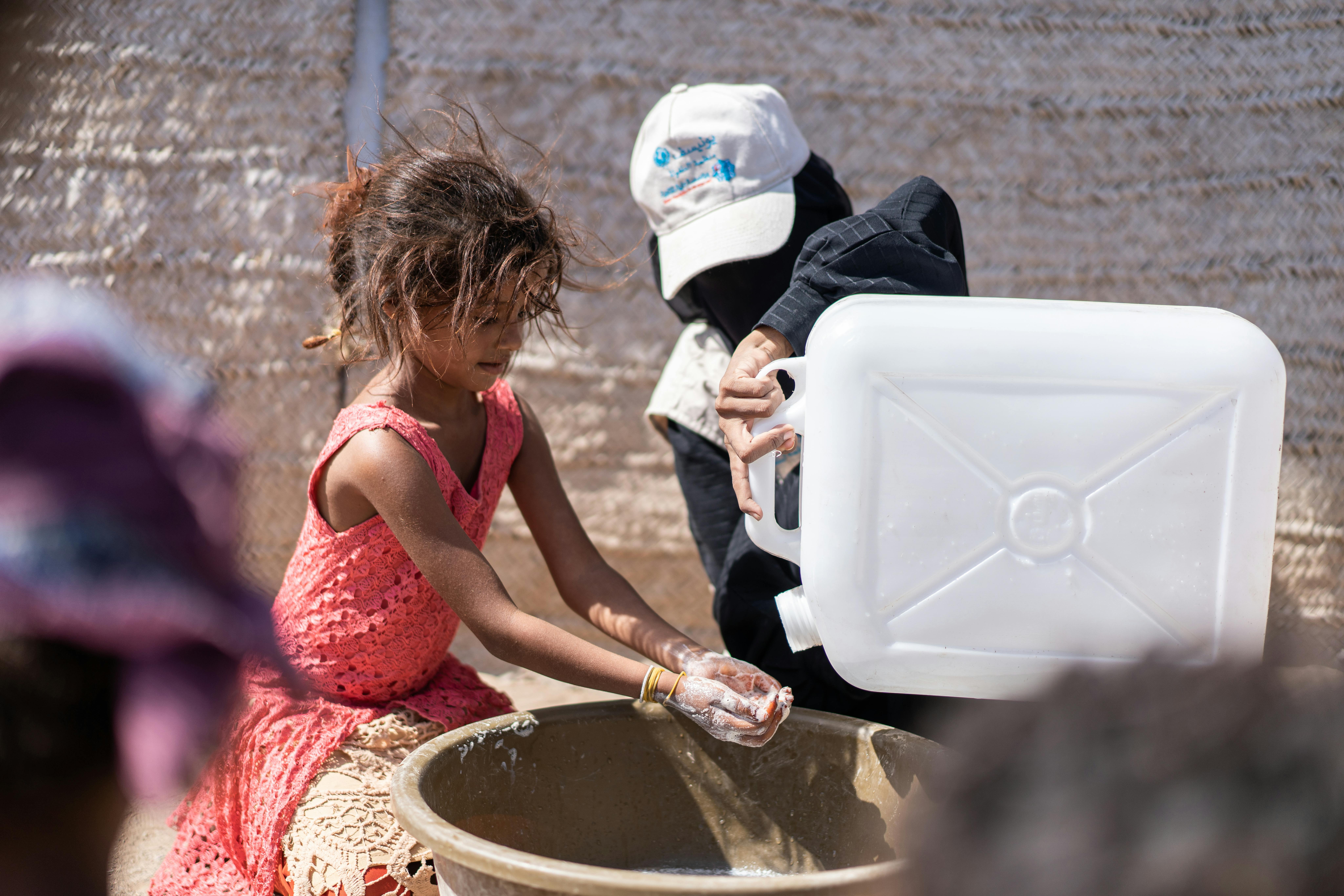 Un'operatrice aiuta questa bambina del campo per sfollati di Al-Alili a lavarsi le mani, con il kit per l'igiene distribuito dall'UNICEF