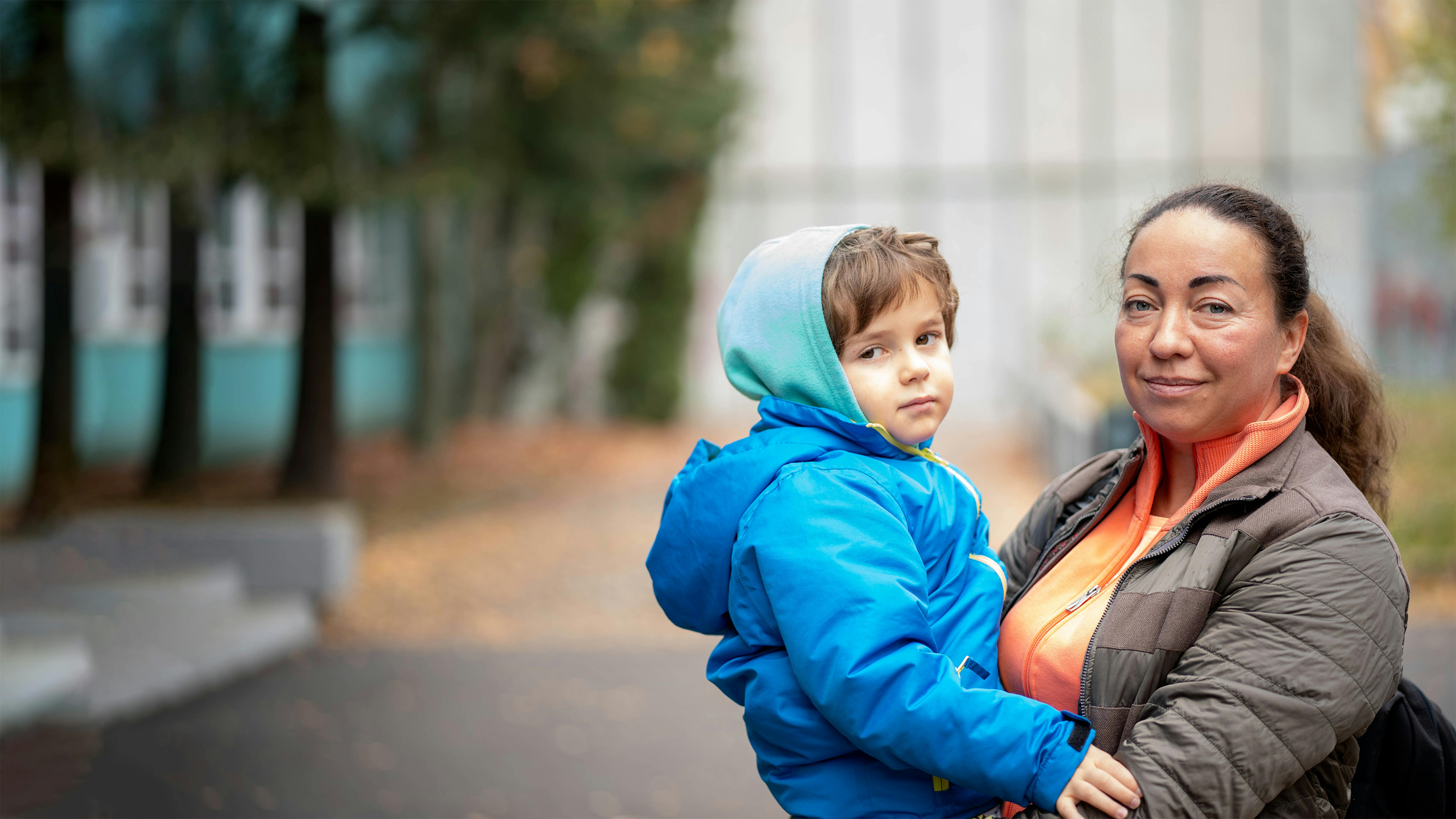 Inna Kolyadinskaya, con in braccio il figlio di 4 anni, Pavel, si trova di fronte al Play and Learning Hub di Dubravka, Bratislava, proprio mentre stanno per tornare a casa.  Qui Inna e Pavel vengono accolti da un terapista e da un educatore che forniscono ulteriore supporto al bambino a cui, già in Ucraina, erano stati diagnosticati problemi di sviluppo.