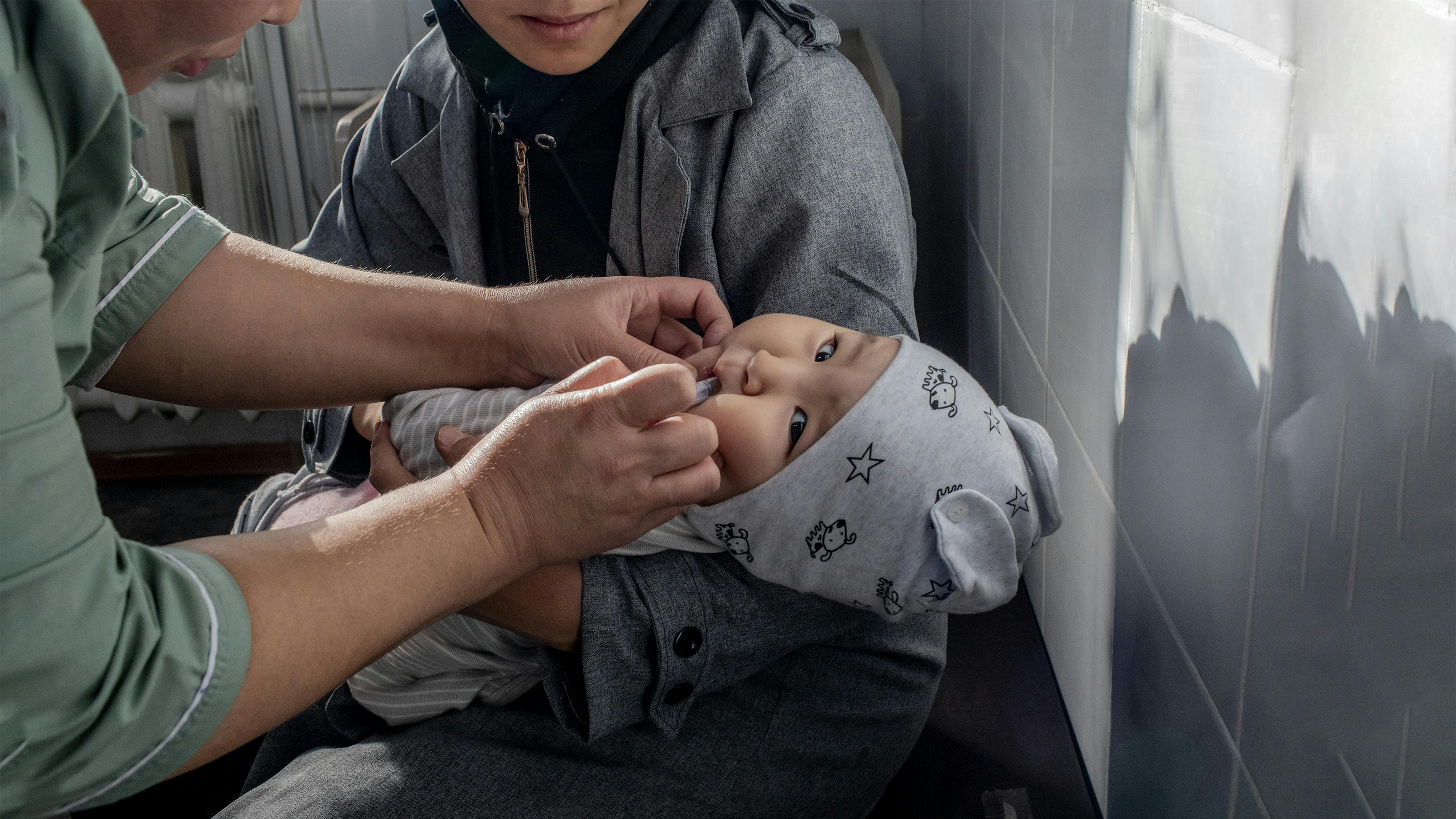 Kirghizistan, Mariam Amirbekova di 11 mesi è trattenuta dalla madre mentre riceve la seconda dose di vaccino pentavalente