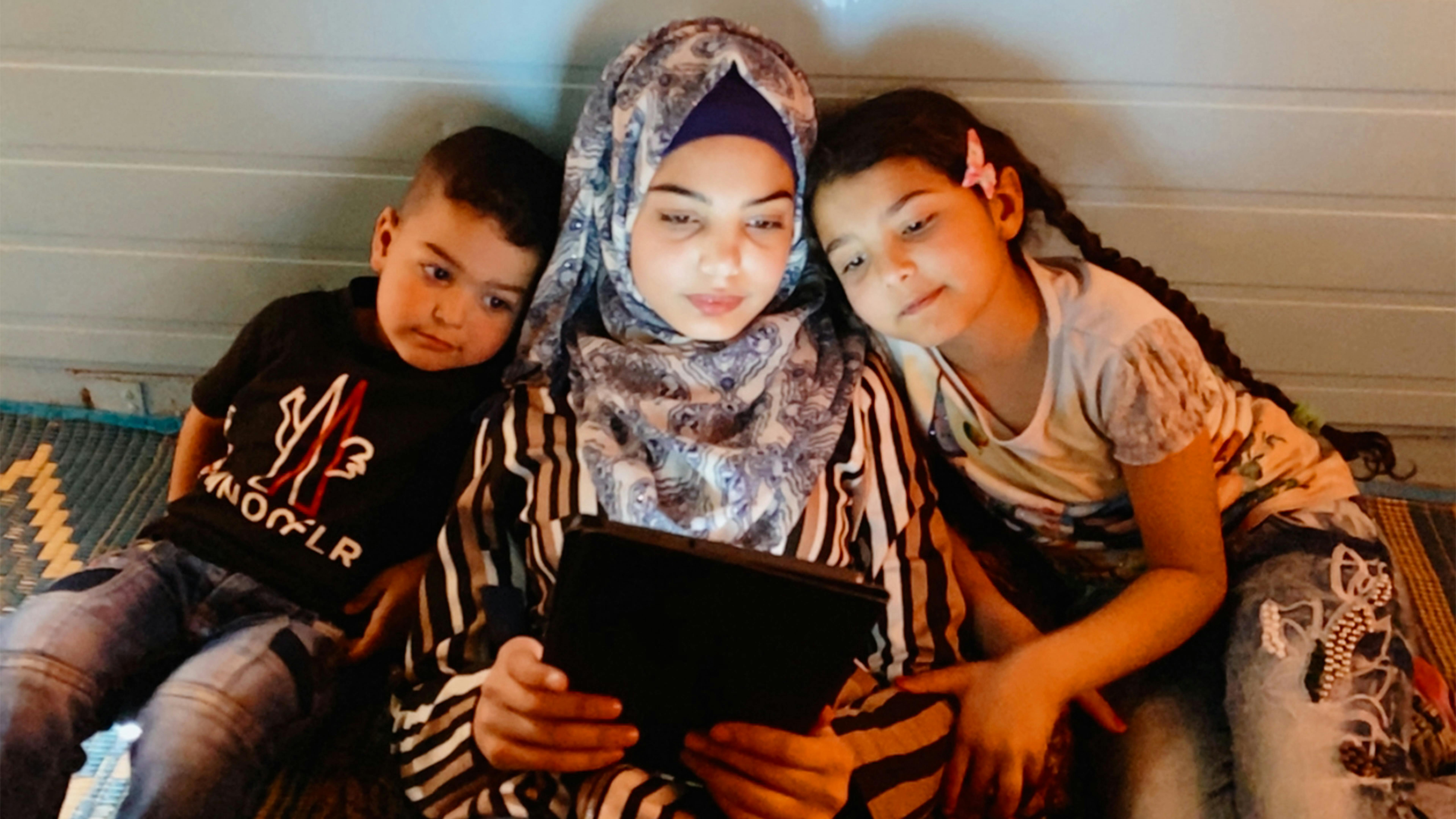 Giordania Hala, 15 anni, insegna alla sorella minore e al fratello come usare un tablet nella loro casa nel campo profughi di Za'atari