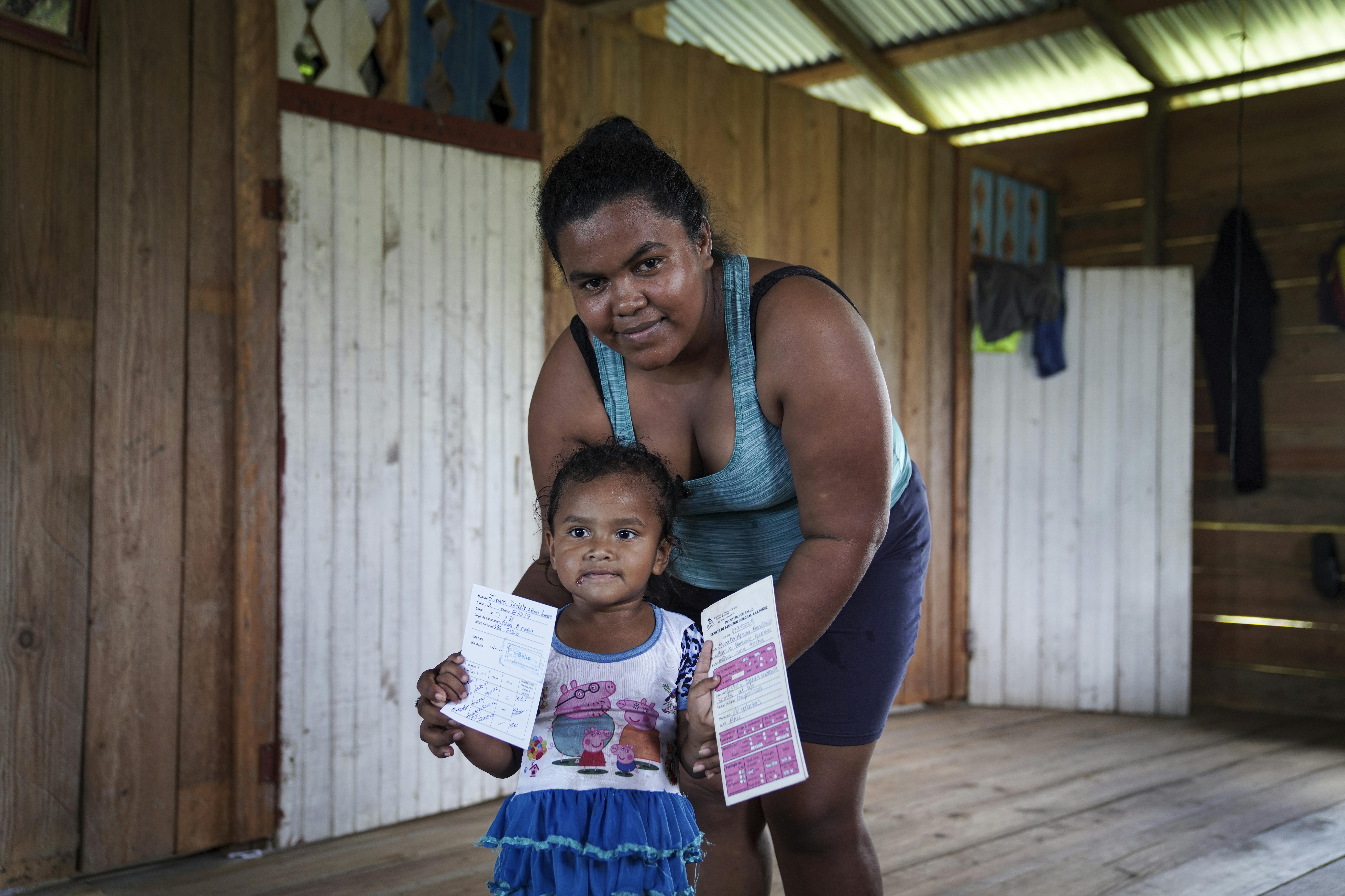 Florencia Mena con la figlia di 3 anni, Rihana, che tiene in mano le sue schede di vaccinazione per mostrarle al personale sanitario. Gli infermieri sono essenziali per la comunità di Sisin, territorio indigeno di Twi Yahabra nei Caraibi del Nord del Nicaragua.