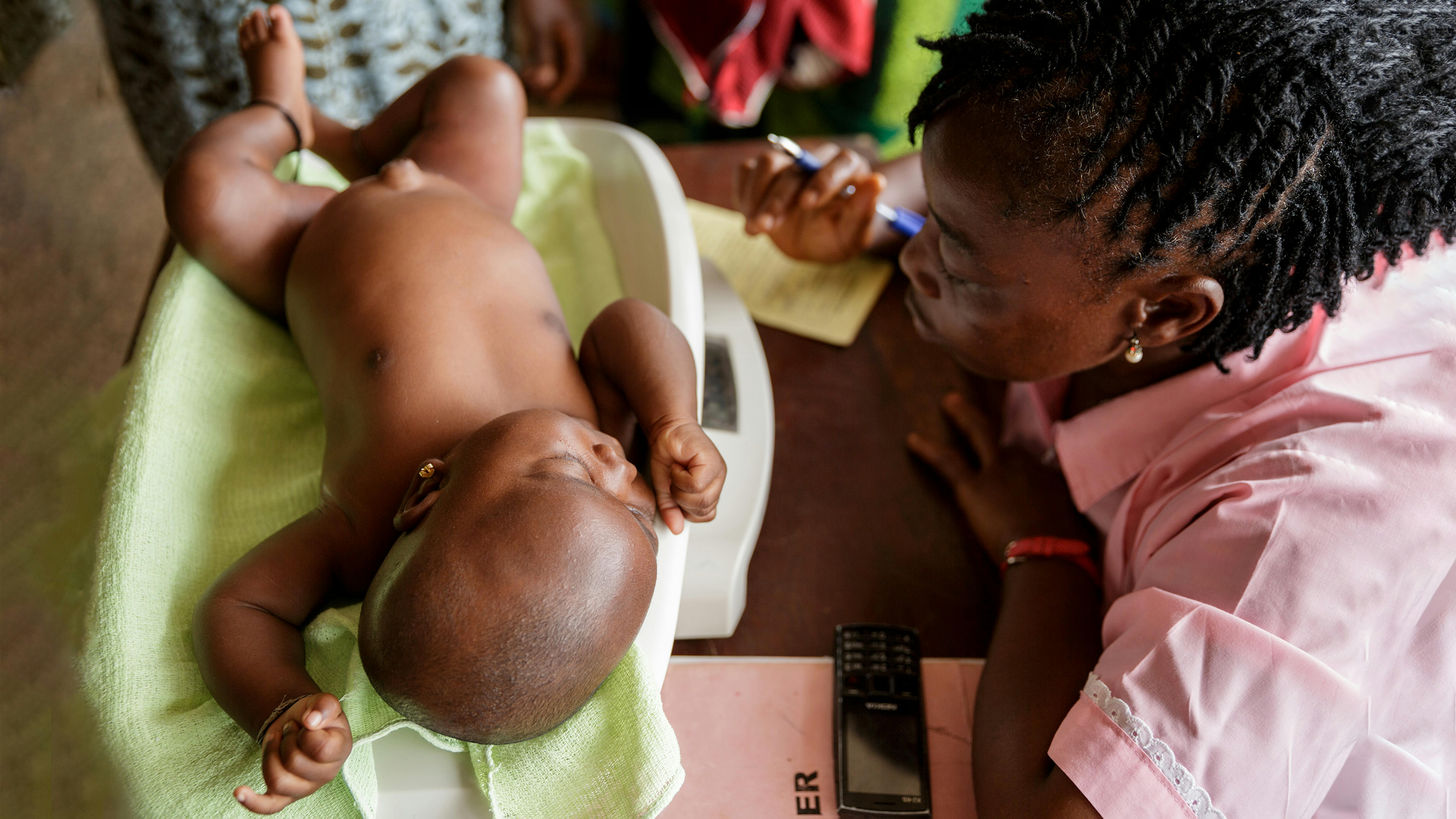 Sierra Leone - Un operatore sanitario registra il peso di una bambina durante il monitoraggio della crescita presso l'ospedale governativo di Kenema a Kenema,