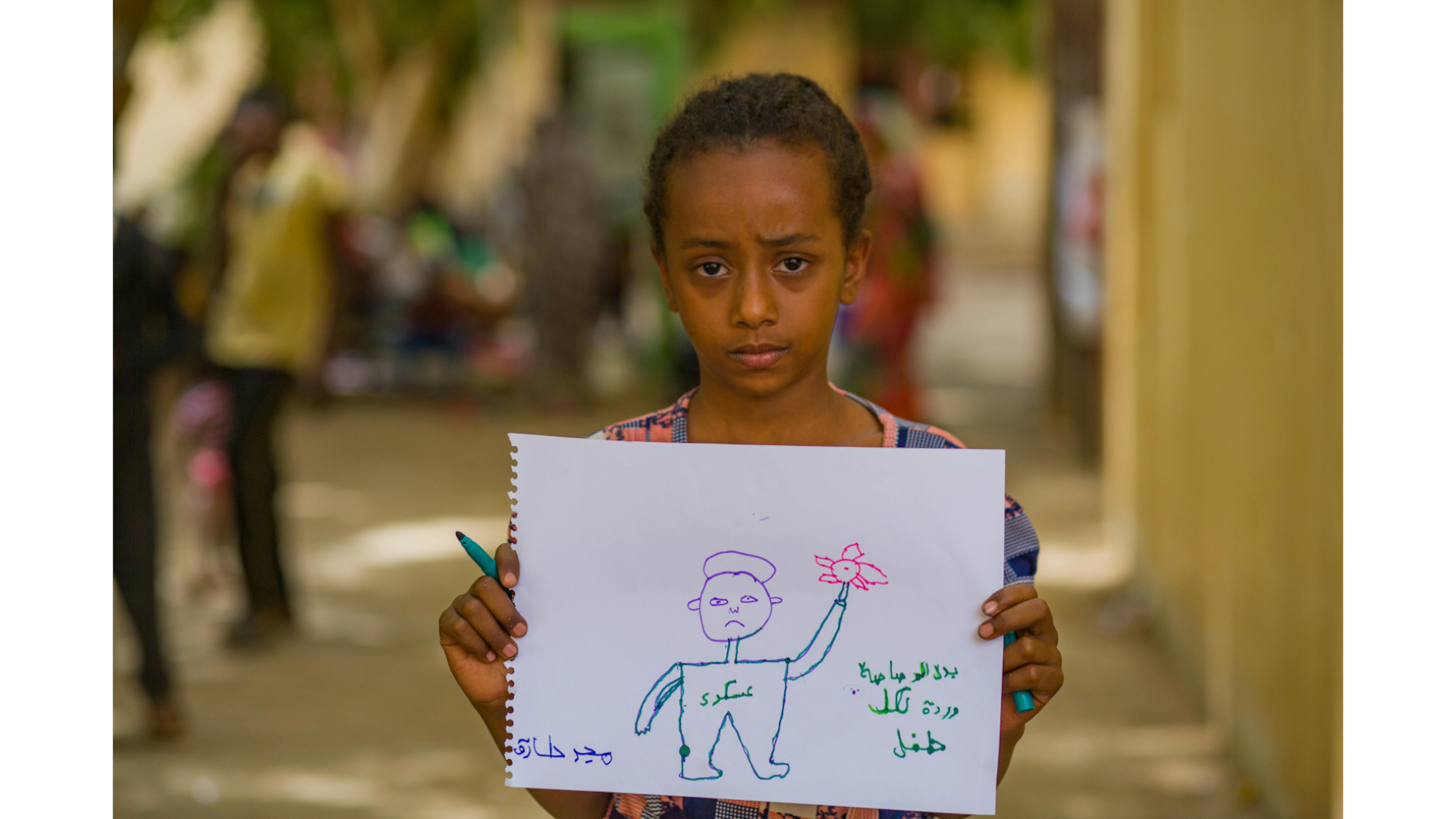 Majd mostra i suoi disegni durante le attività psicosociali in un centro di raccolta a Madani.