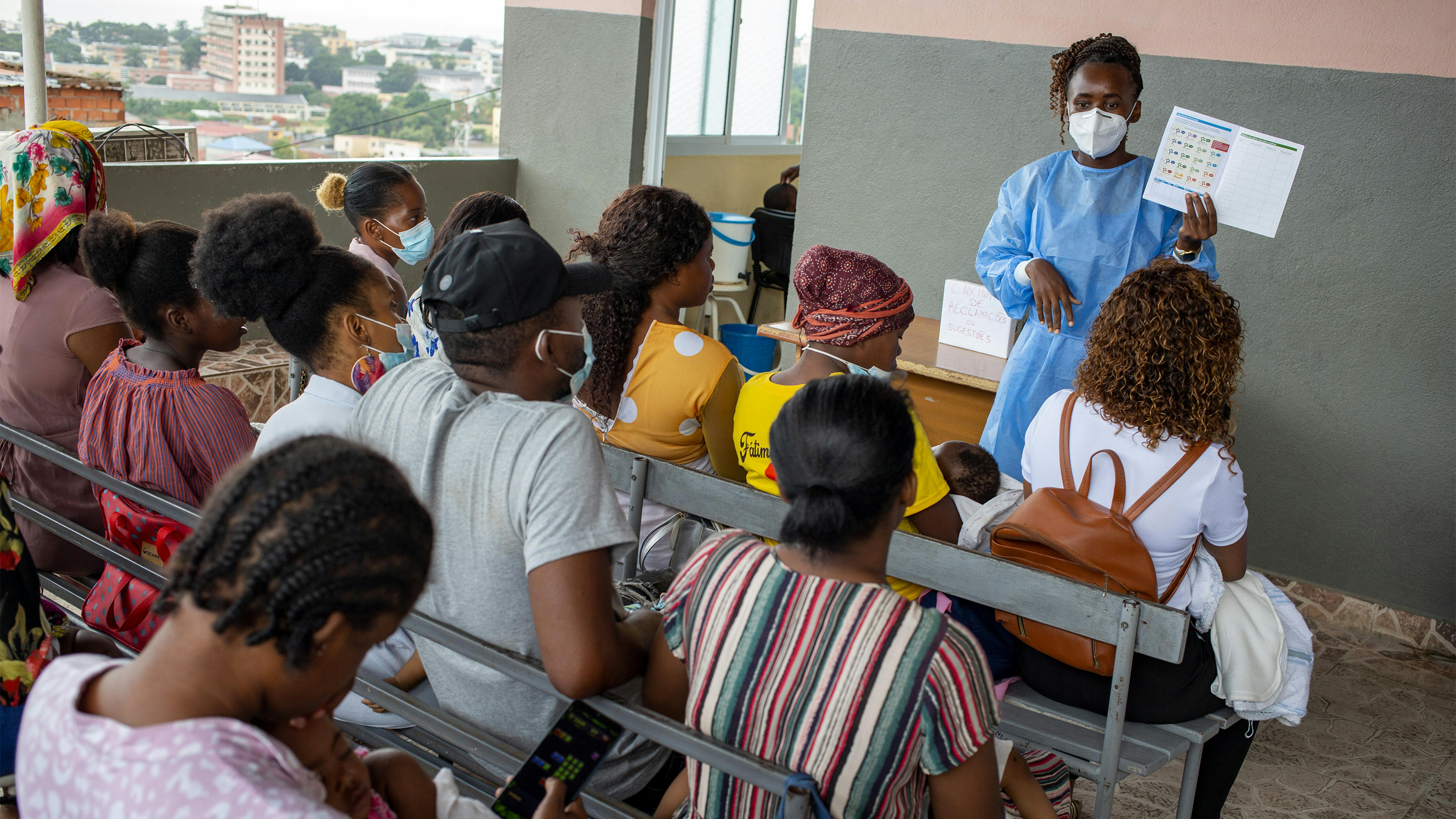 Angola, genitori e tutori aspettano che i loro figli ricevano le vaccinazioni di routine al Catambor Health Centre, mentre ascoltano l'infermiera Quénia Pinto (a sinistra) spiegare come funzionano i programmi di vaccinazione dei bambini.