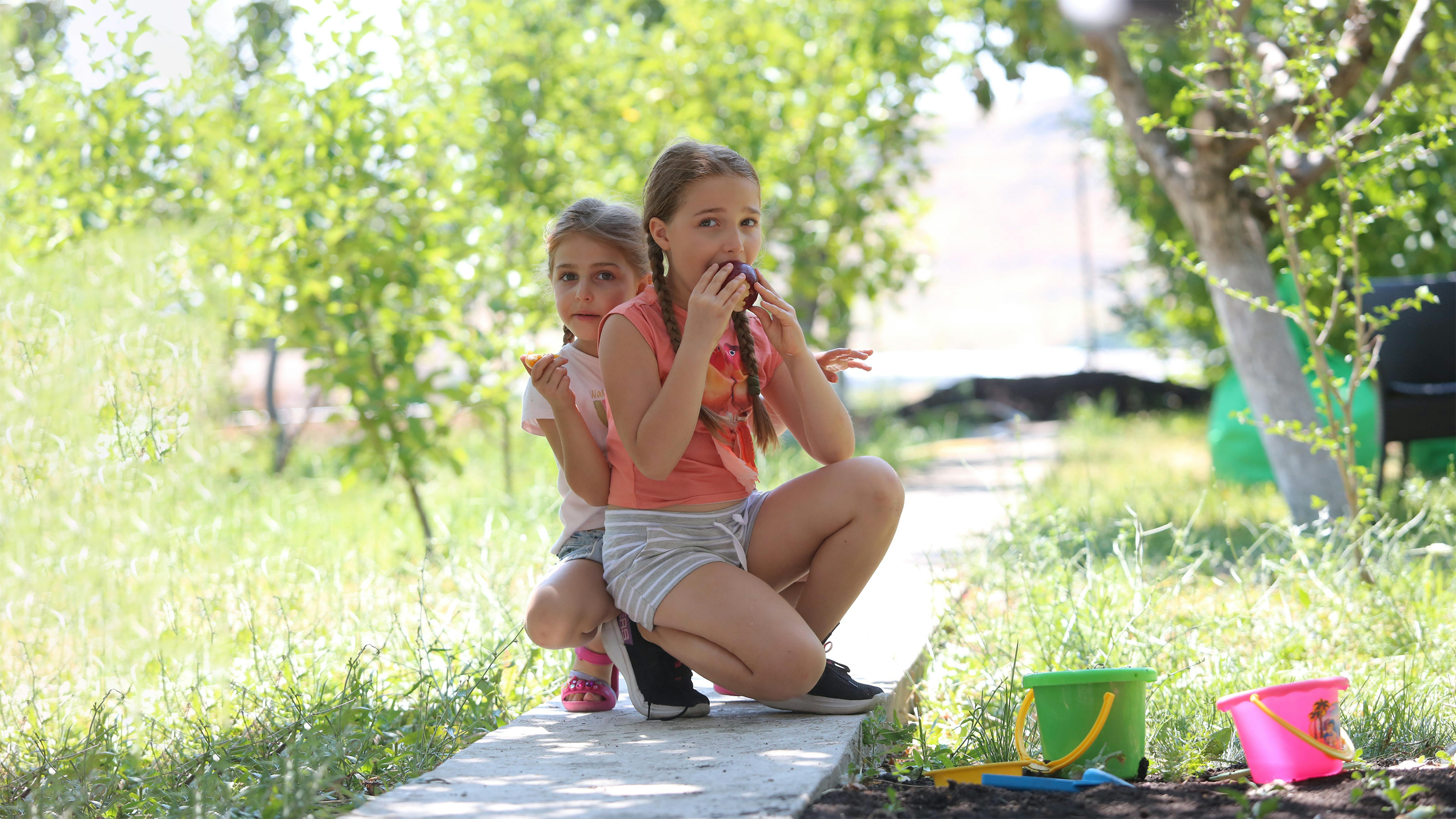 Armenia Due ragazze mangiano i frutti dell'orto della loro casa di campagna durante una vacanza in famiglia....