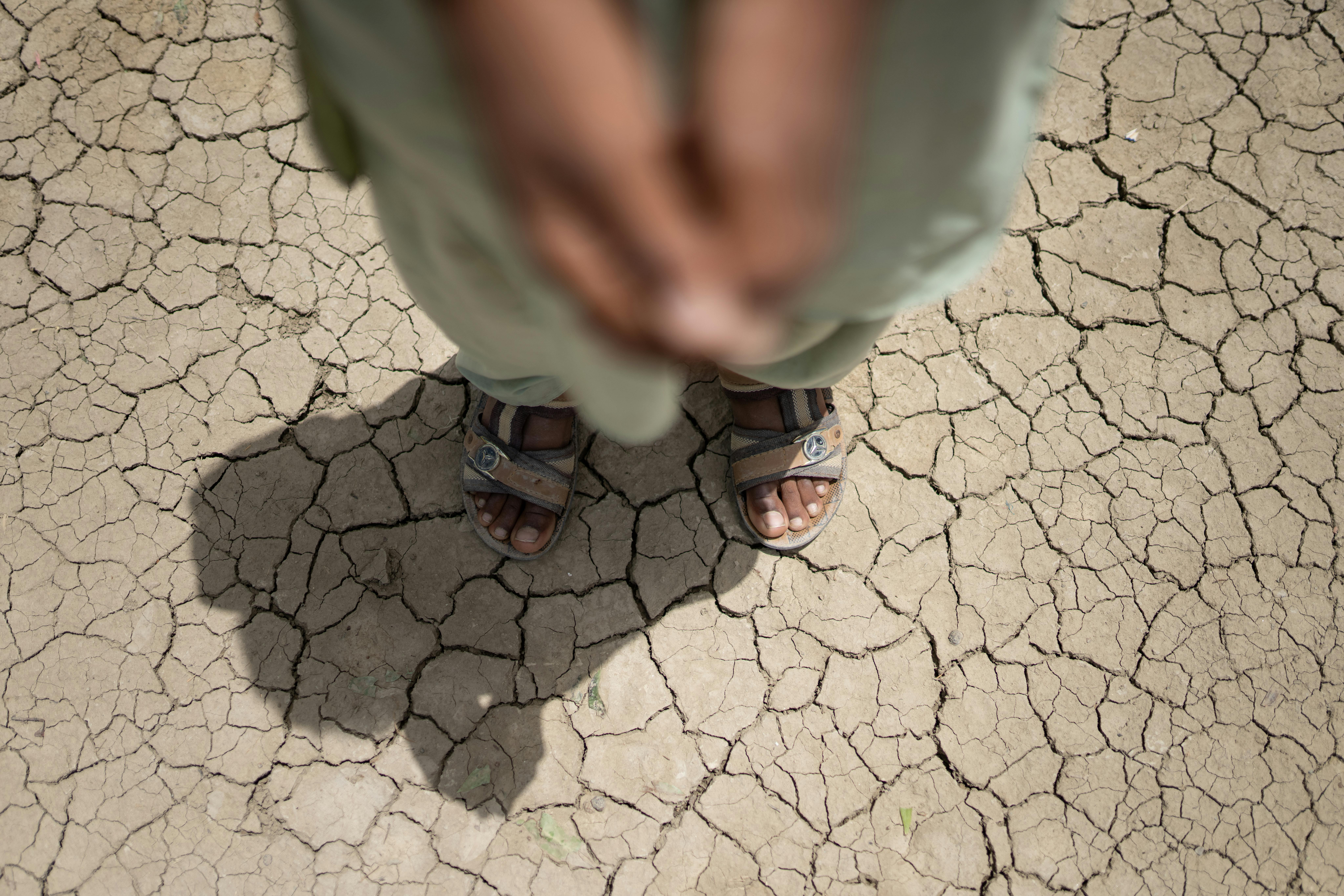 Pakistan, piedi di un bambino che calpesta il terreno arido nel Punjab. A otto mesi dalle catastrofiche inondazioni in Pakistan, le condizioni meteorologiche estreme mostrano pochi segni di cedimento.
