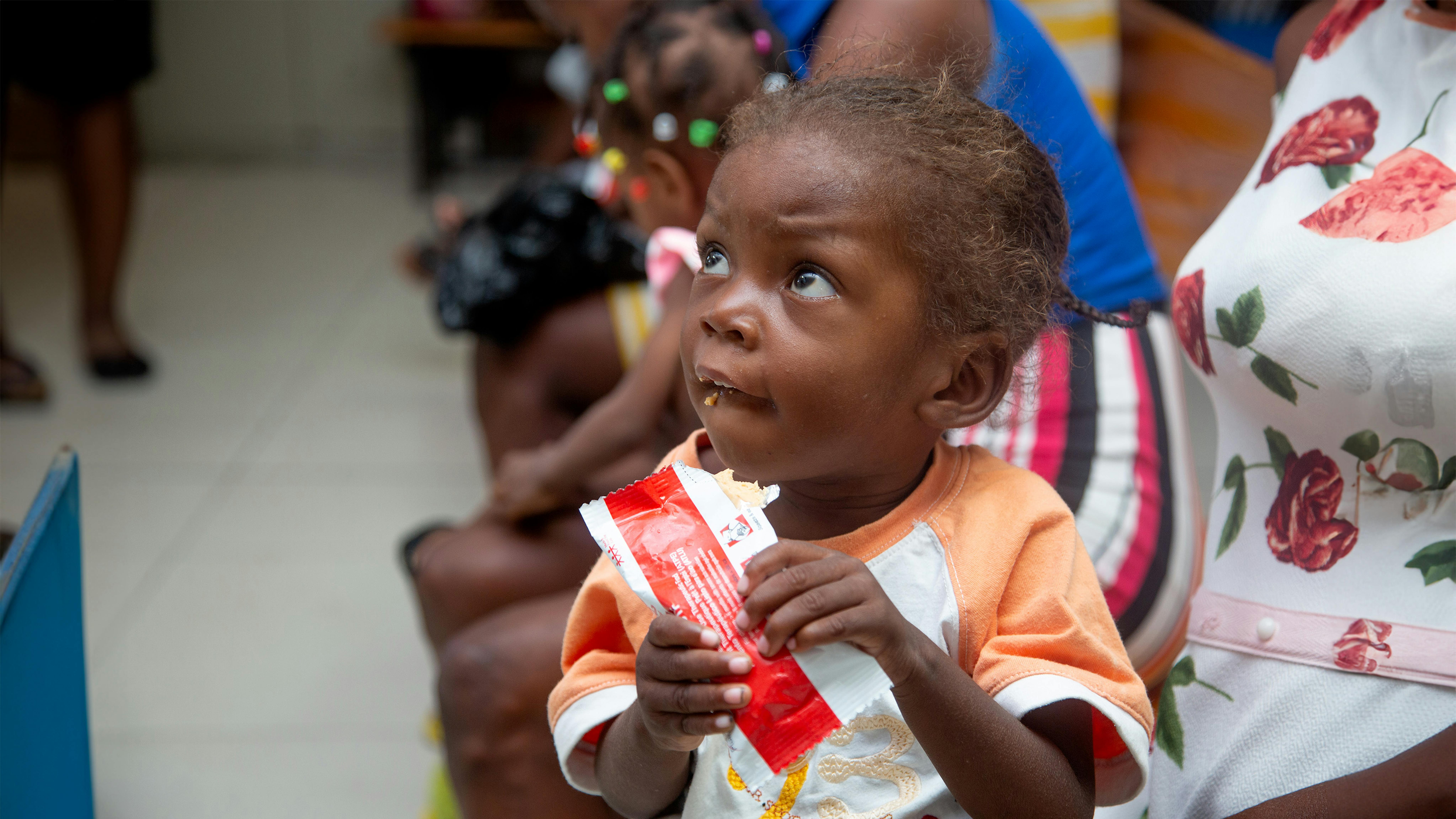 Haiti un bambino mangia una bustina di cibo terapeutico pronto all'uso (RUTF) nel  centro GHESKIO, partner dell'UNICEF