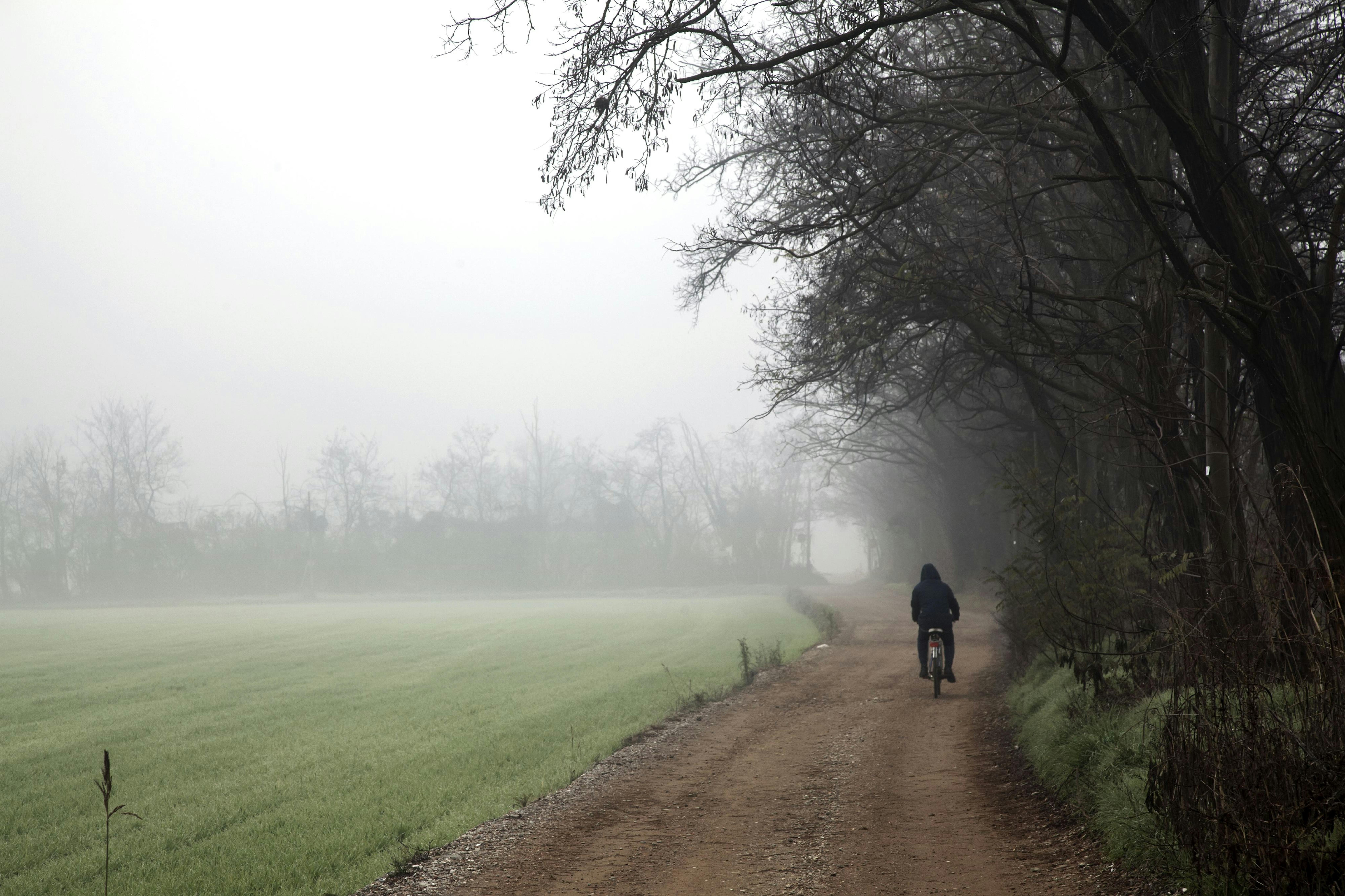 Un ragazzo pedala lungo un sentiero immerso nella nebbia