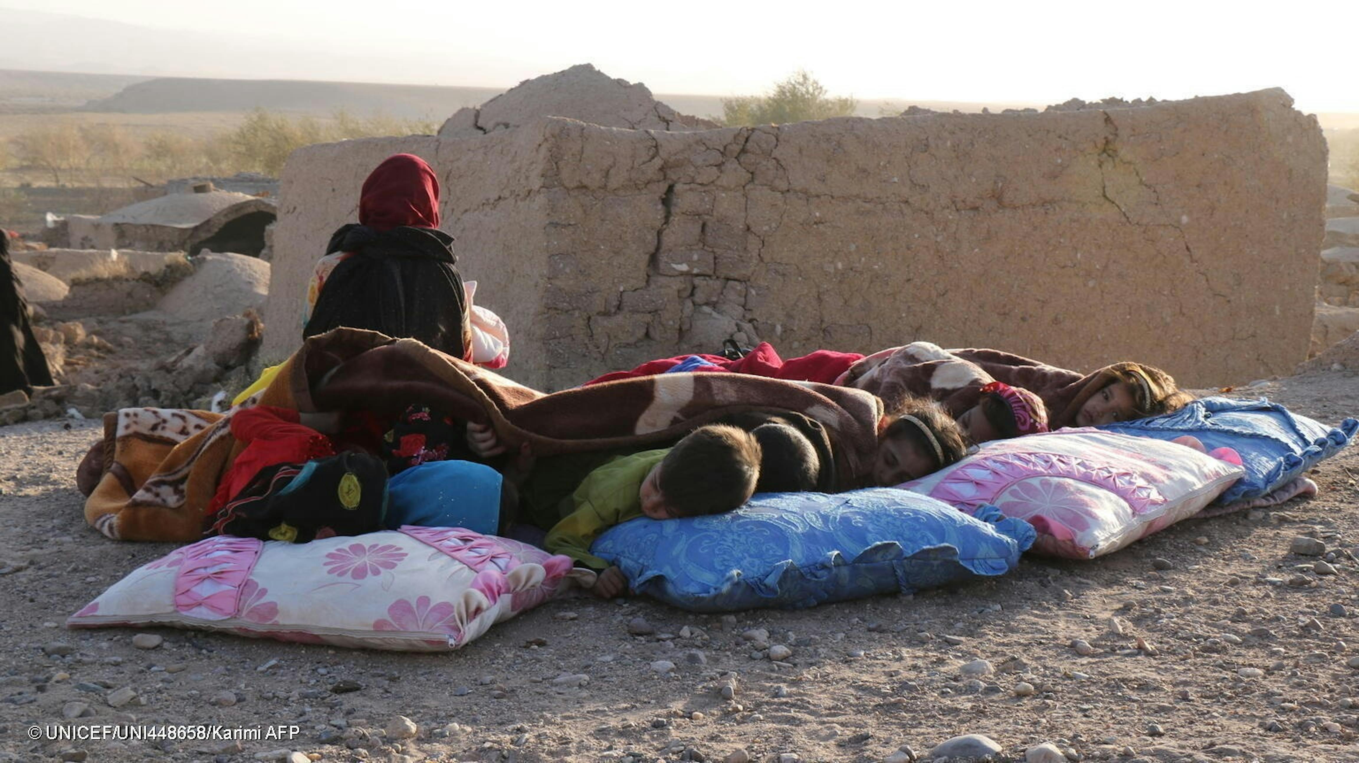Bambini adagiati su cuscini dormono all'esterno delle macerie delle loro abitazioni nel villaggio di Serbuland, nel distretto di Zinda Jan, epicentro del sisma che nella mattina del 7 ottobre 2023 ha colpito la provincia di Herat (Afghanistan) provocando un grande numero di vittime, feriti e sfollati - © UNICEF/UNI448658/Karimi AFP