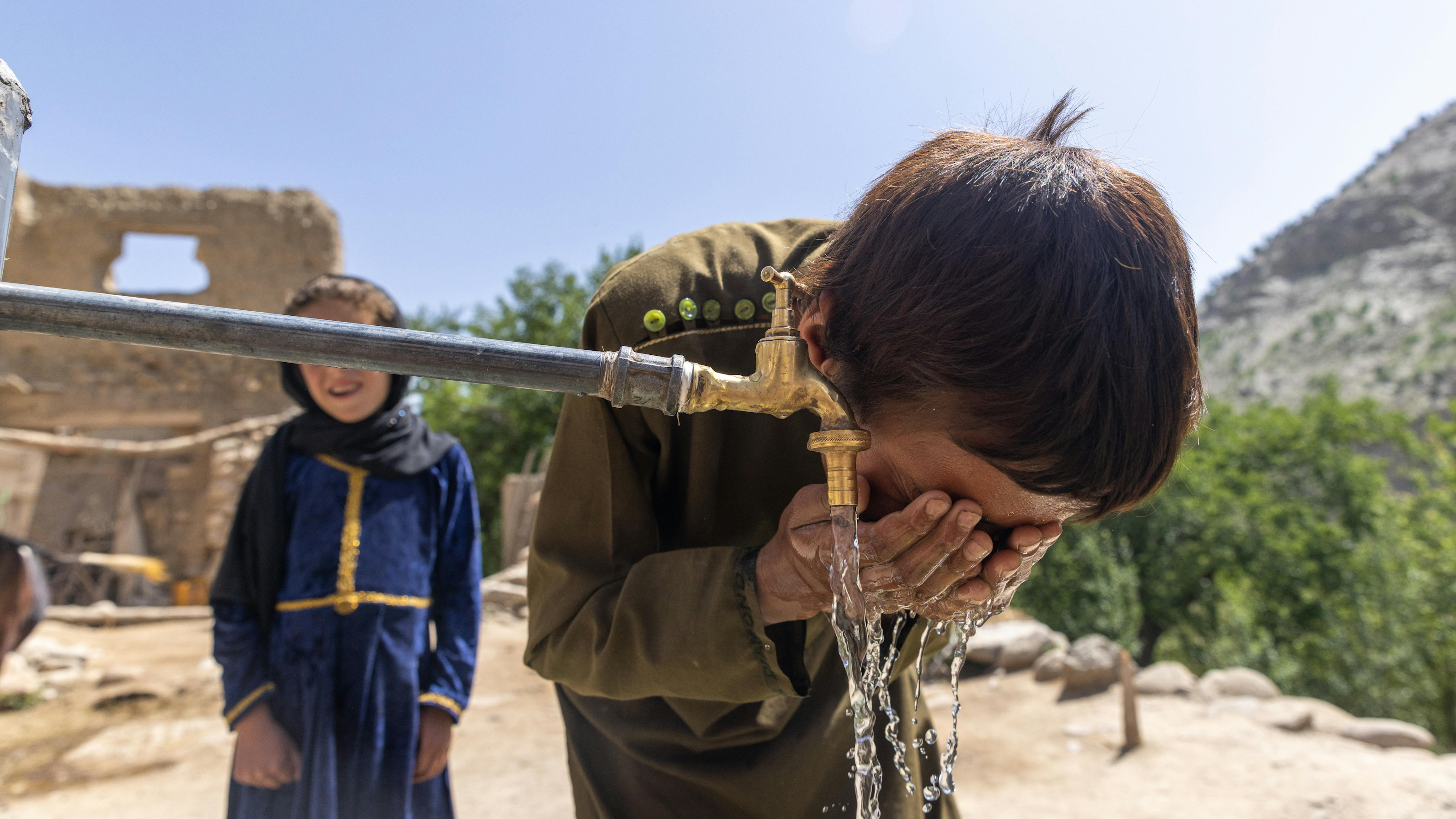 Afghanistan - Mohammad Shah, 9 anni, si rinfresca ad un nuovo rubinetto dell'acqua
